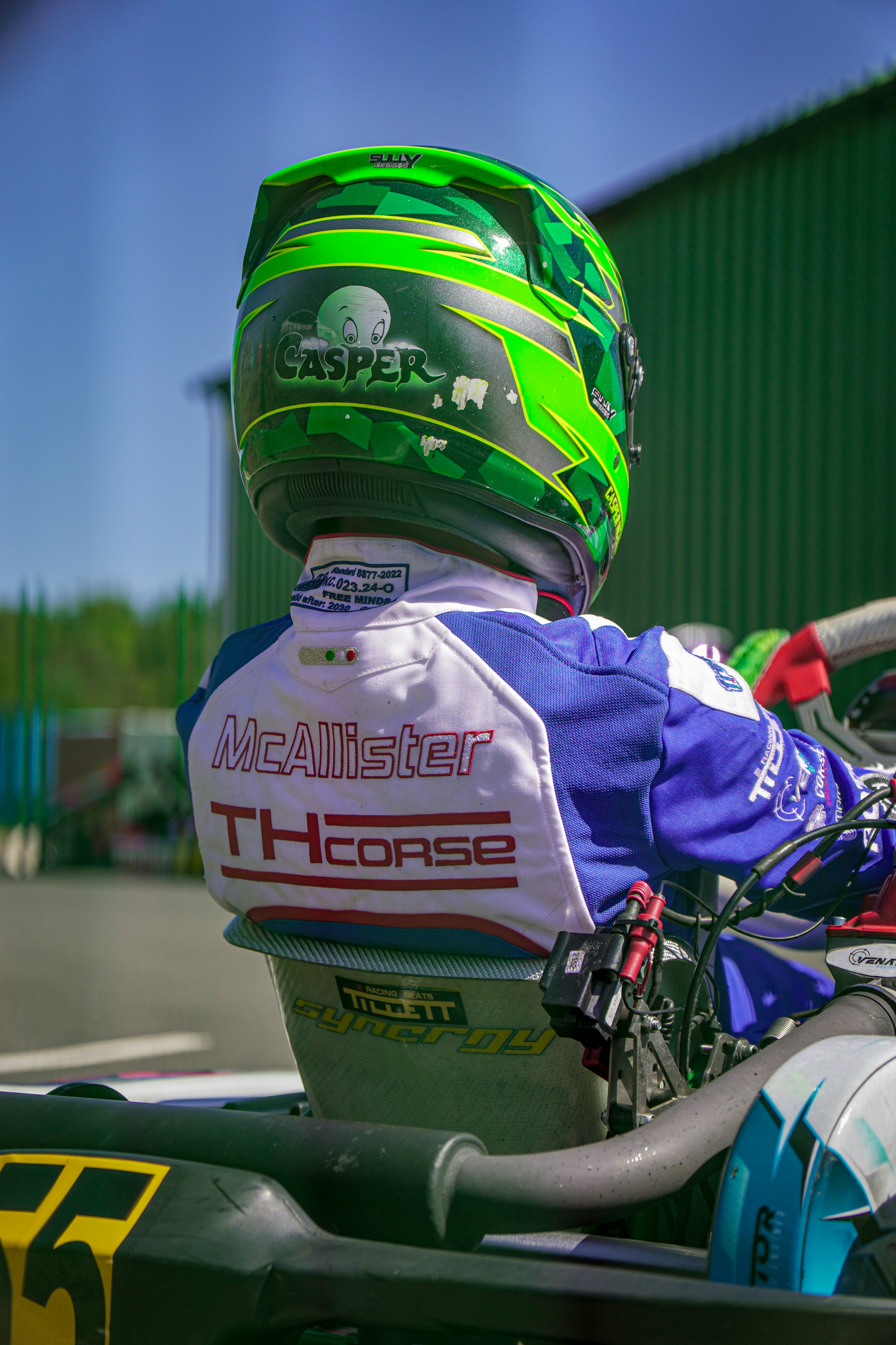 Go-kart racer wearing a green helmet and racing suit.