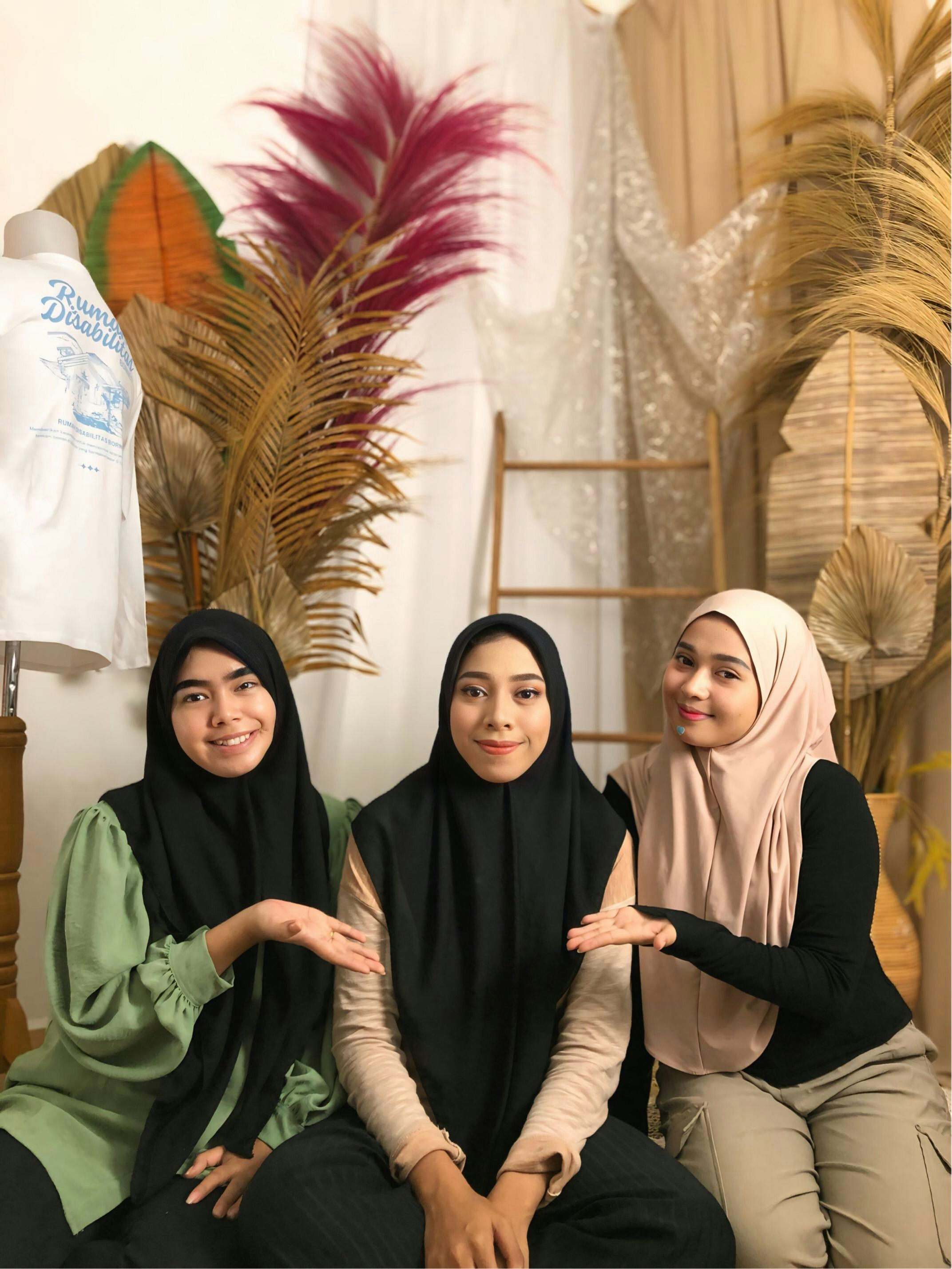 Tiga wanita tersenyum berpose dengan dekorasi.