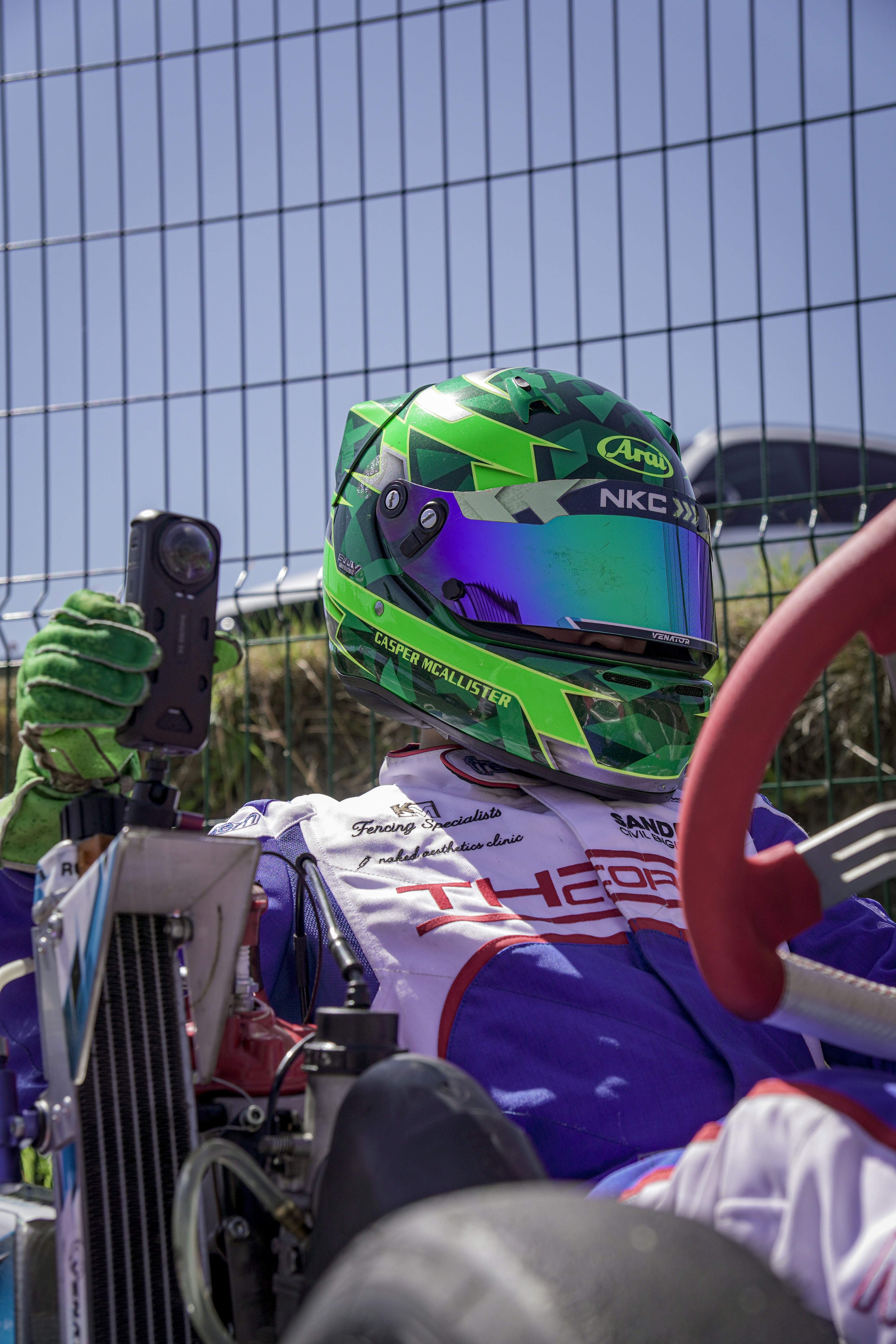 Go-kart racer in green helmet with camera attached camera