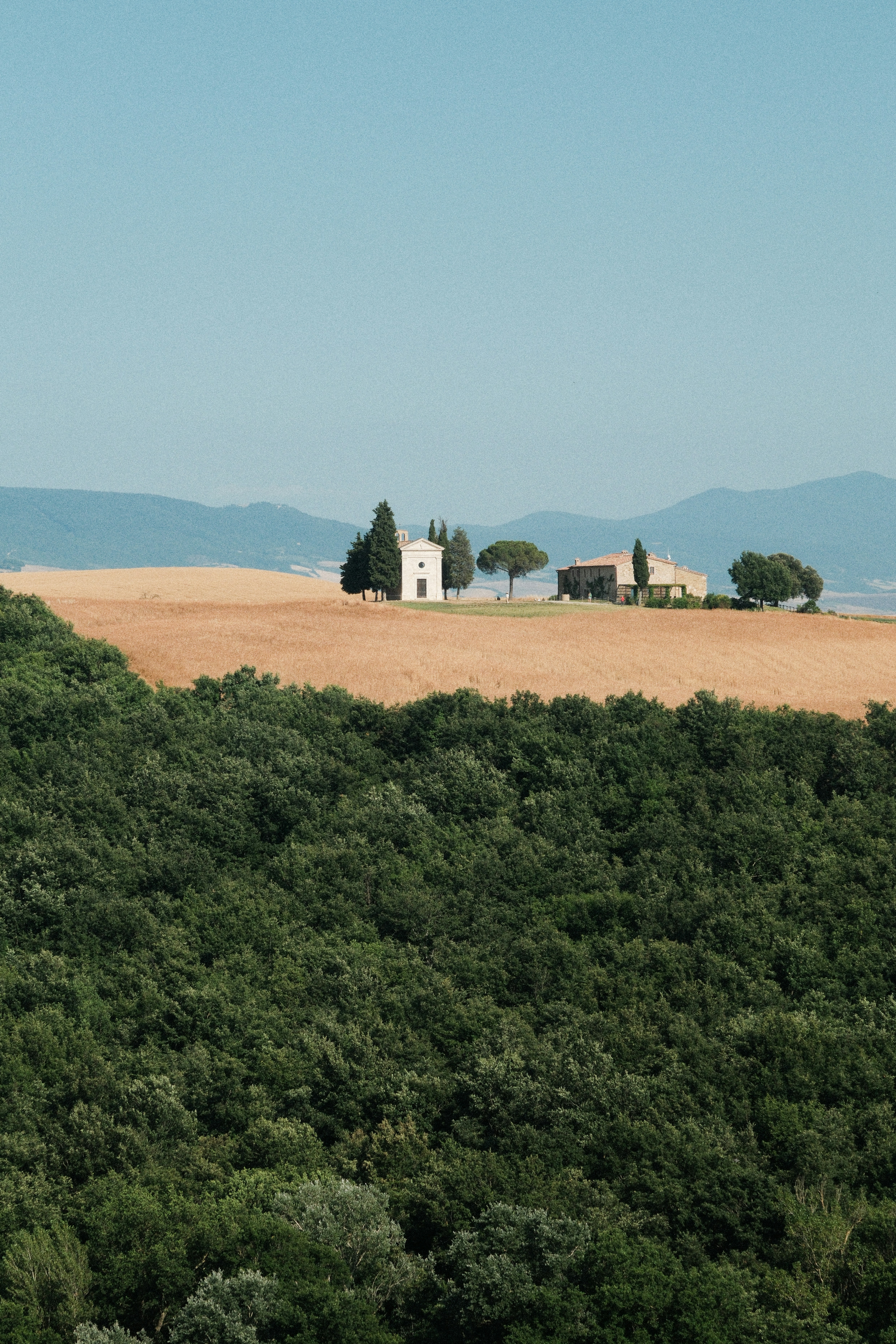 Rolling tuscan hills with a chapel and farmhouse.