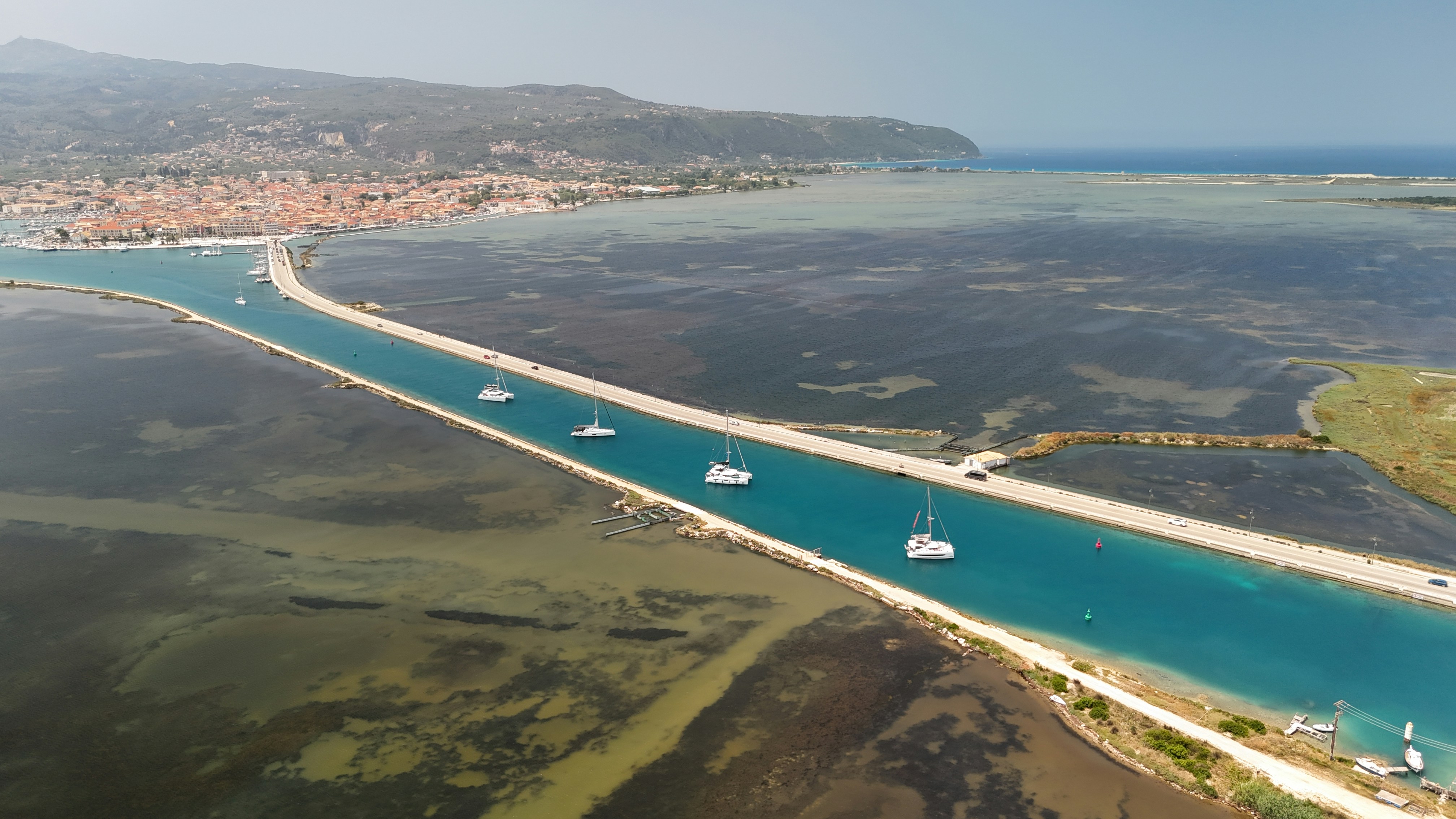 Boats sail through a channel to the sea.
