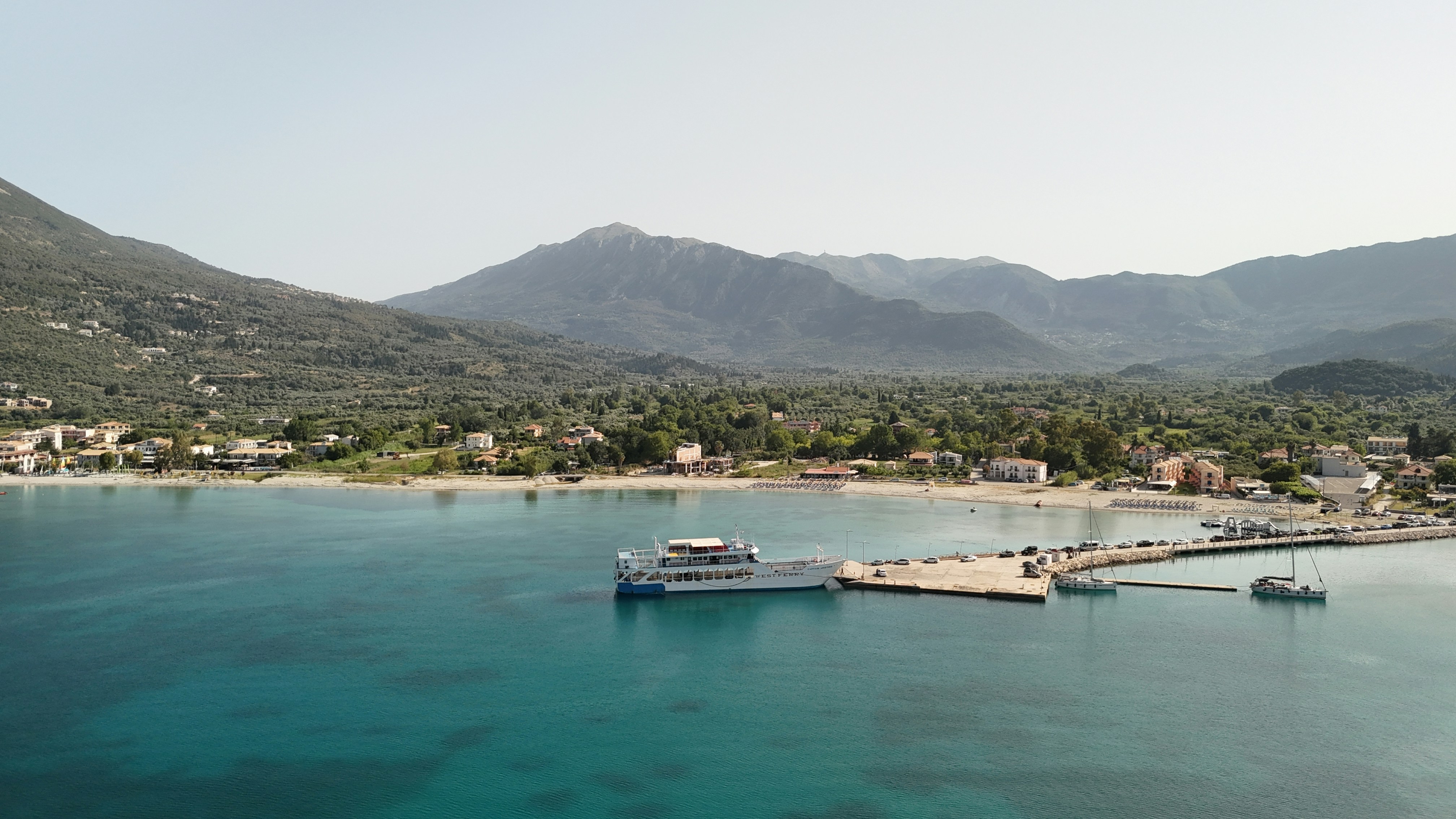 A ferry docks near a beautiful seaside village.