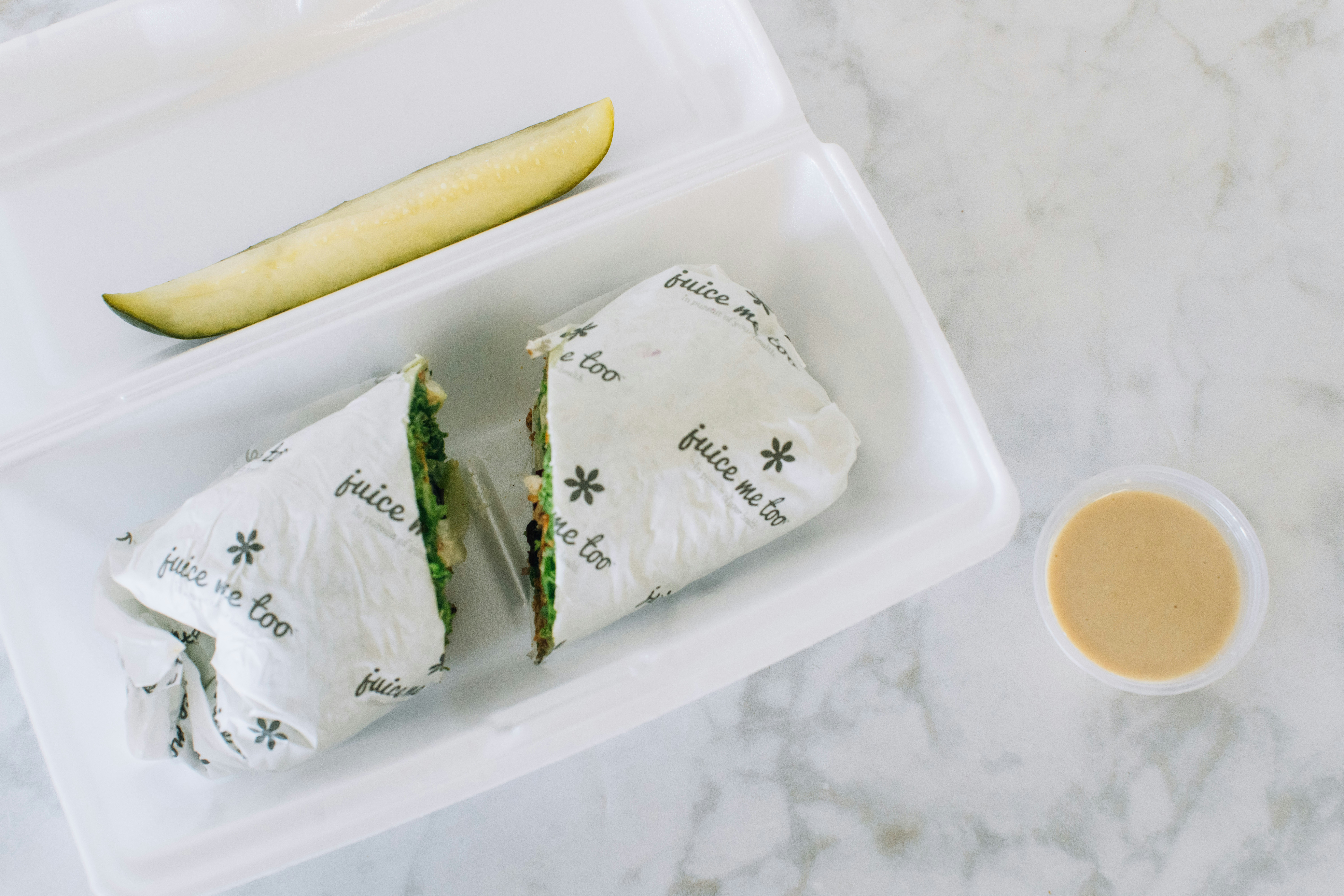 A wrap, pickle, and sauce in a box.