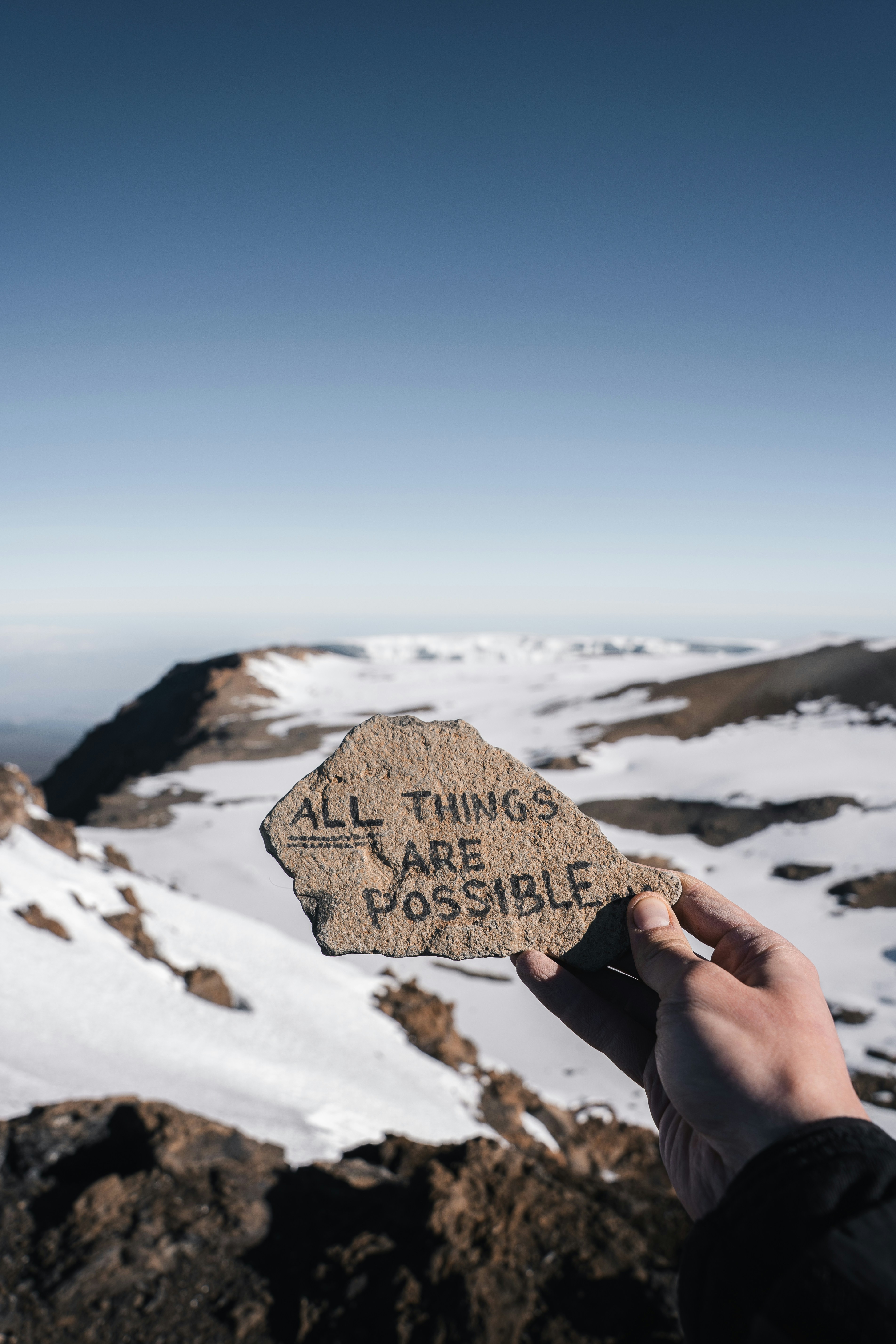 Person holds rock with encouraging message on snowy mountain