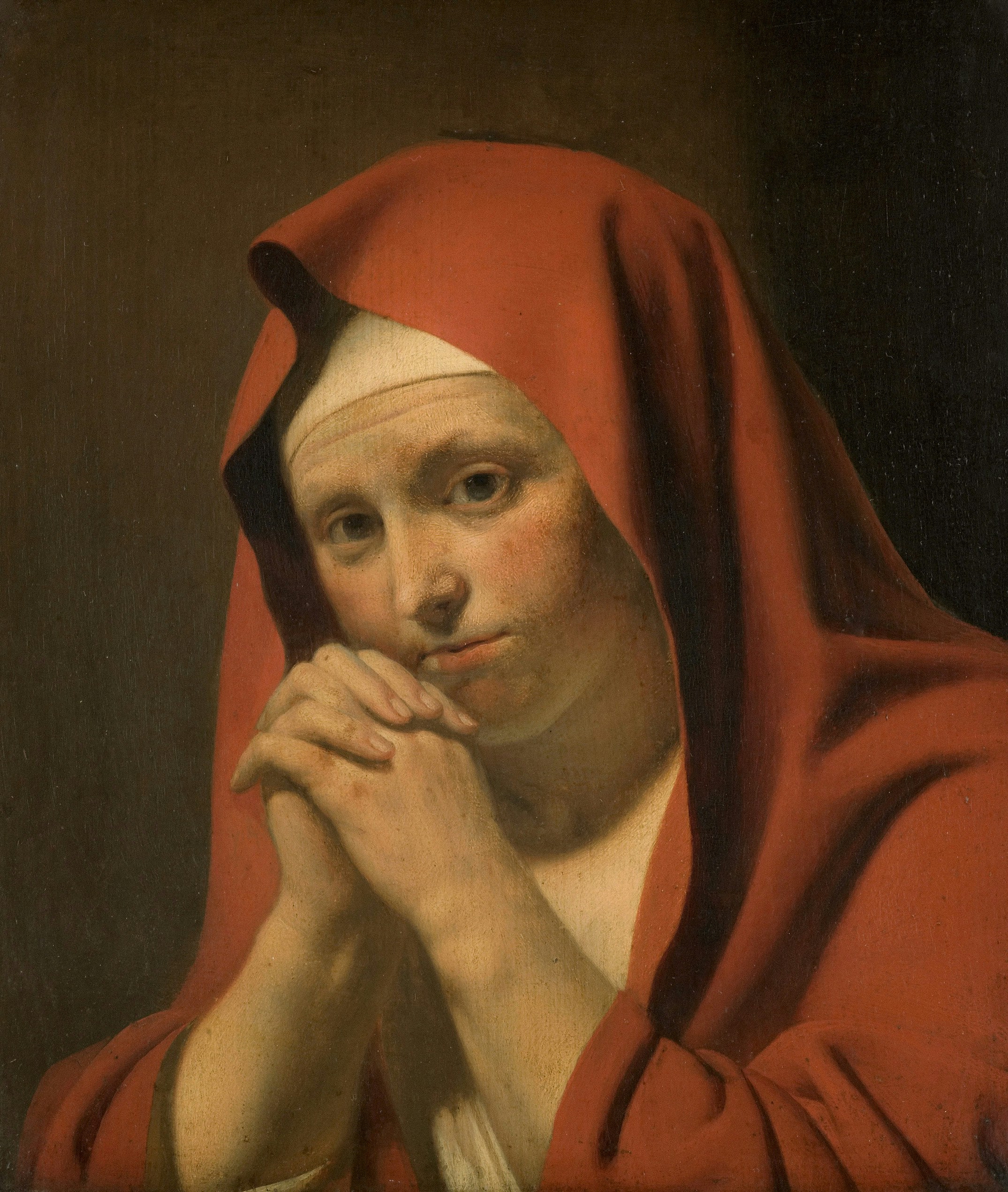 Woman in red hood with hands clasped
