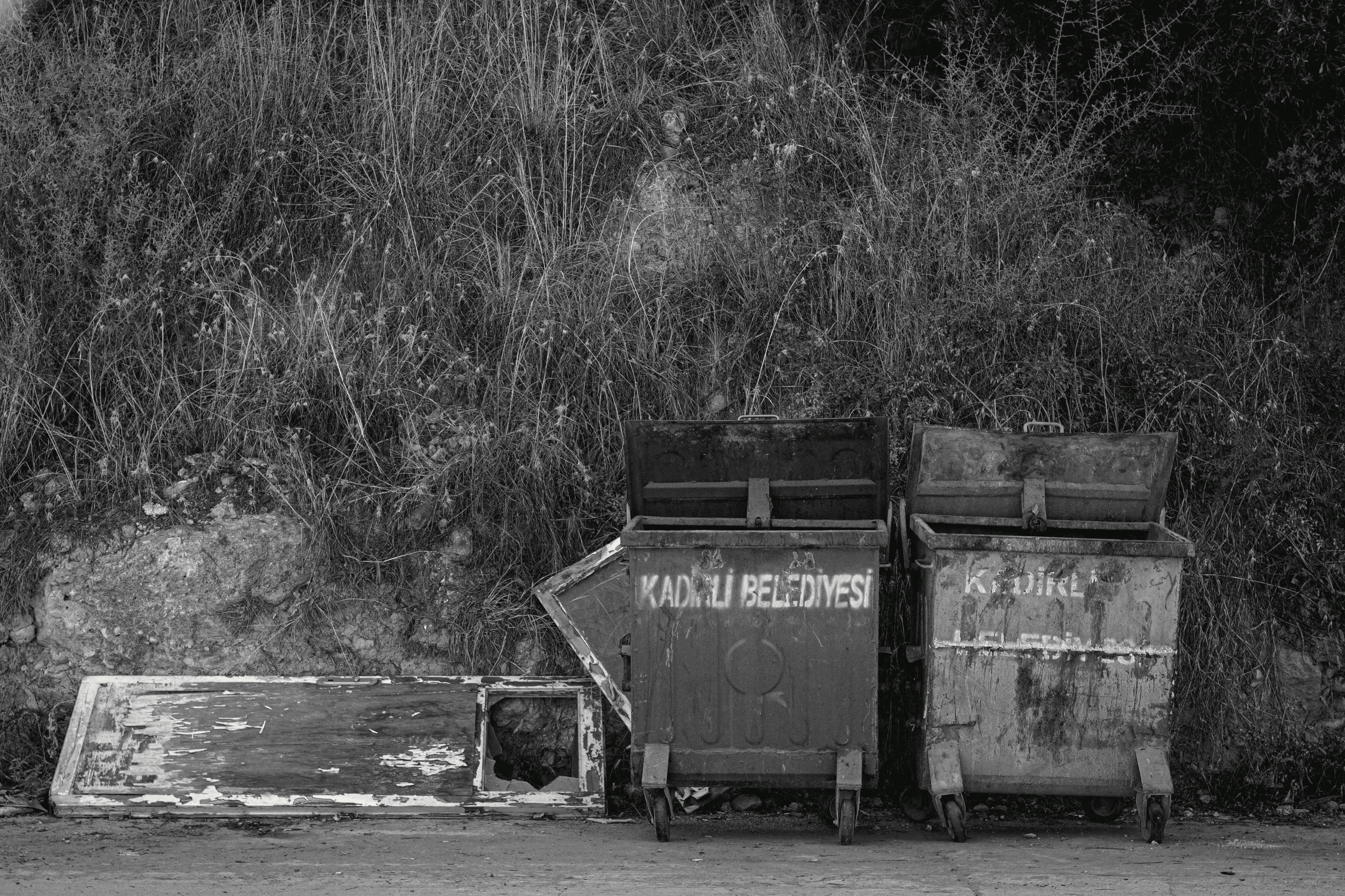 Two trash bins stand beside debris.