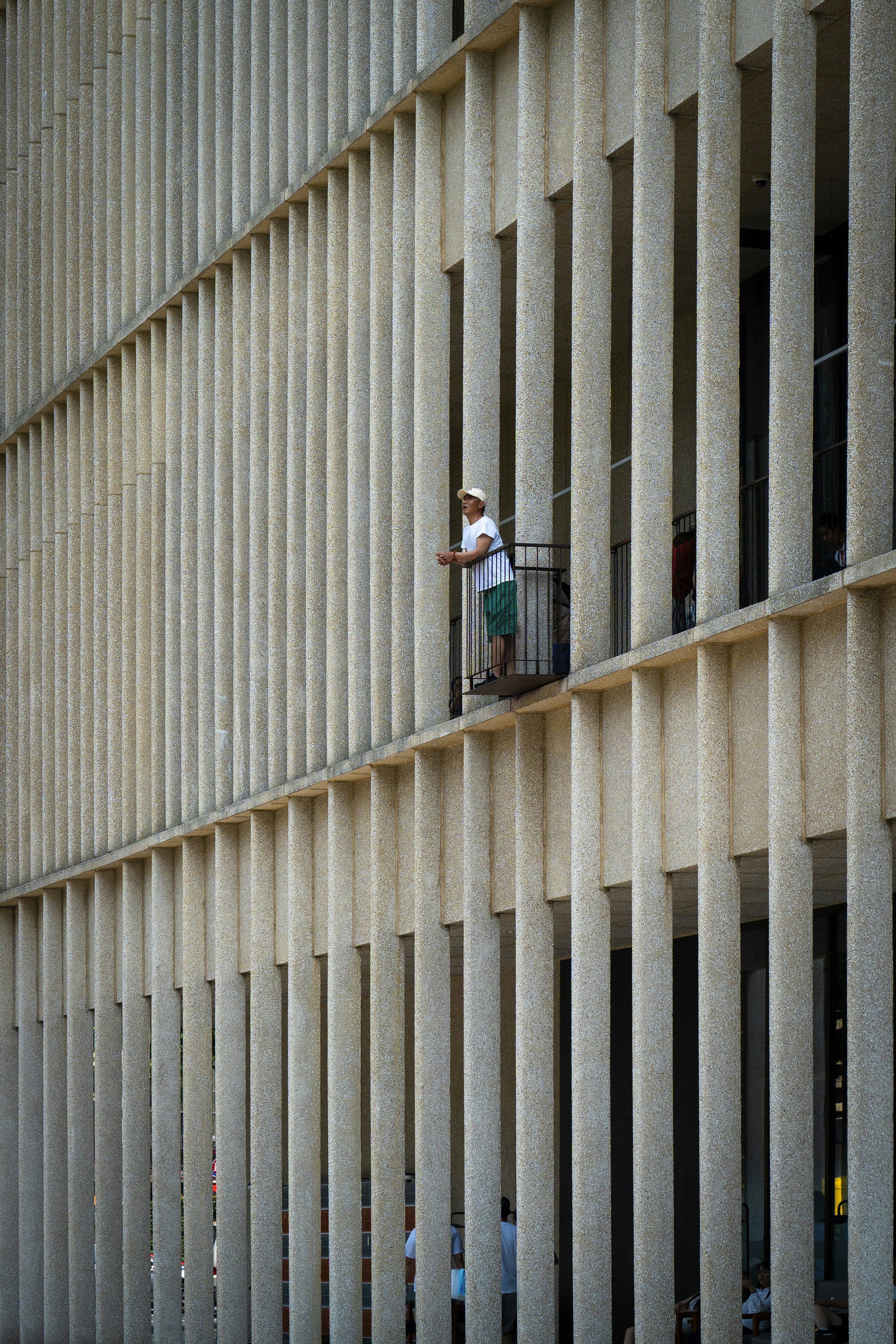 A man stands on a balcony in a building.