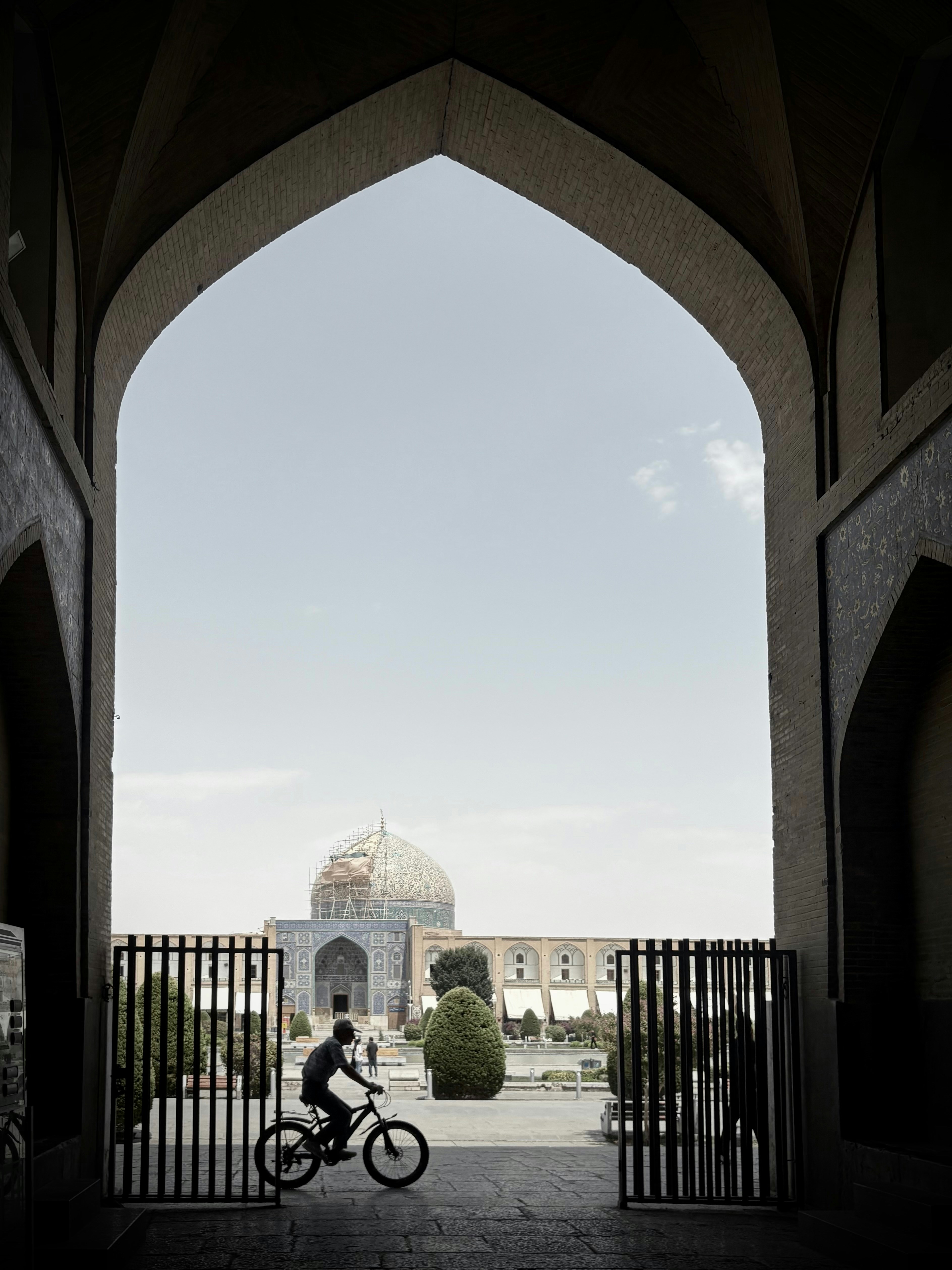 Ein Radfahrer fährt durch einen Torbogen in der Nähe einer Moschee hinein.