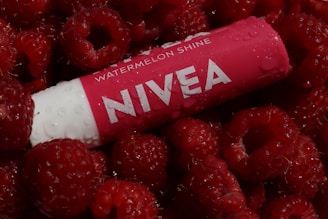 Nivea lip balm rests among fresh raspberries.
