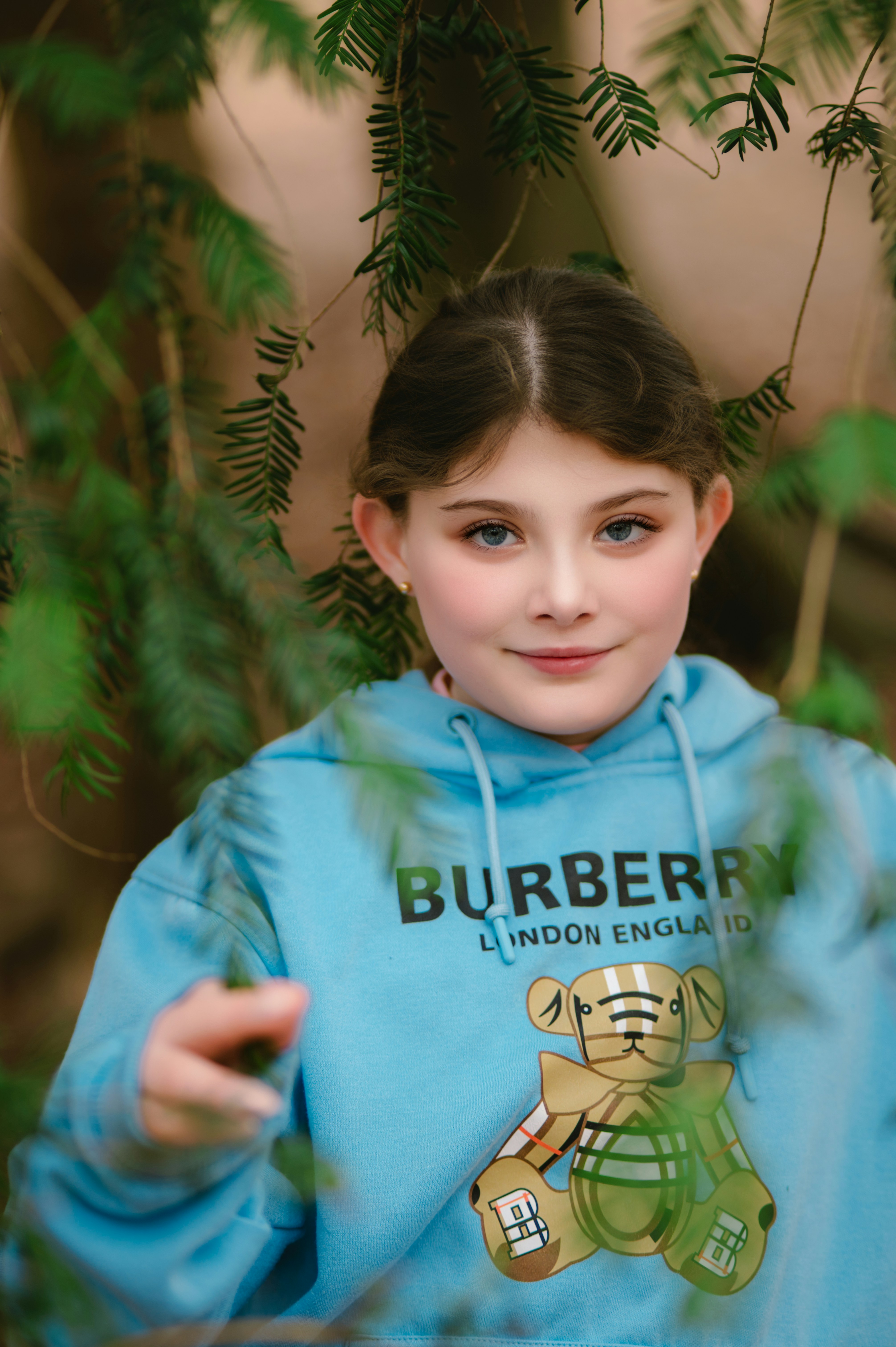 Young girl smiles, wearing a burberry hoodie.