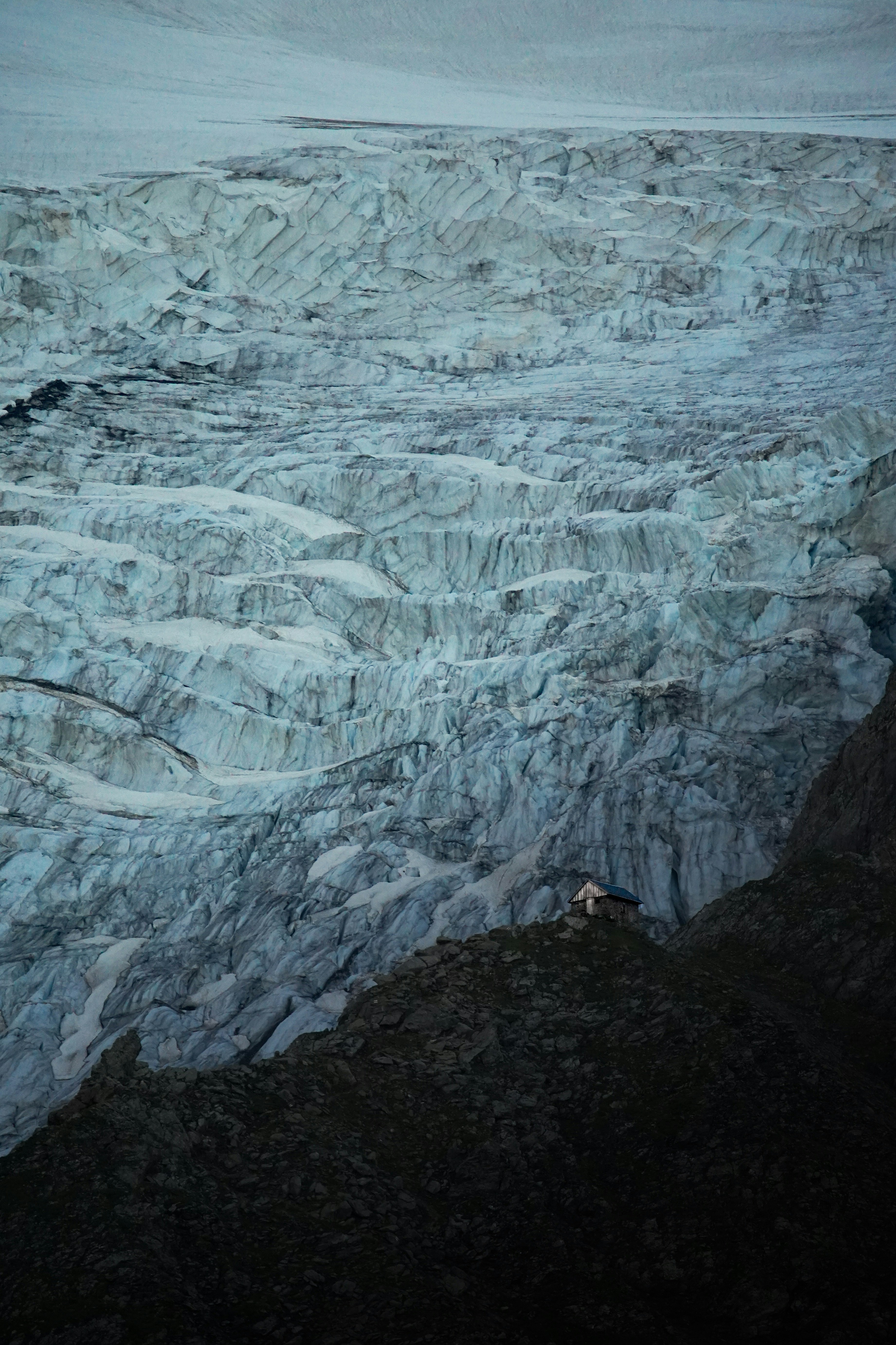 Ein majestätischer Gletscher thront über einer dunklen Klippe.