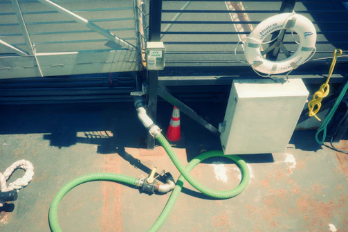 A green hose on a deck near a boat.