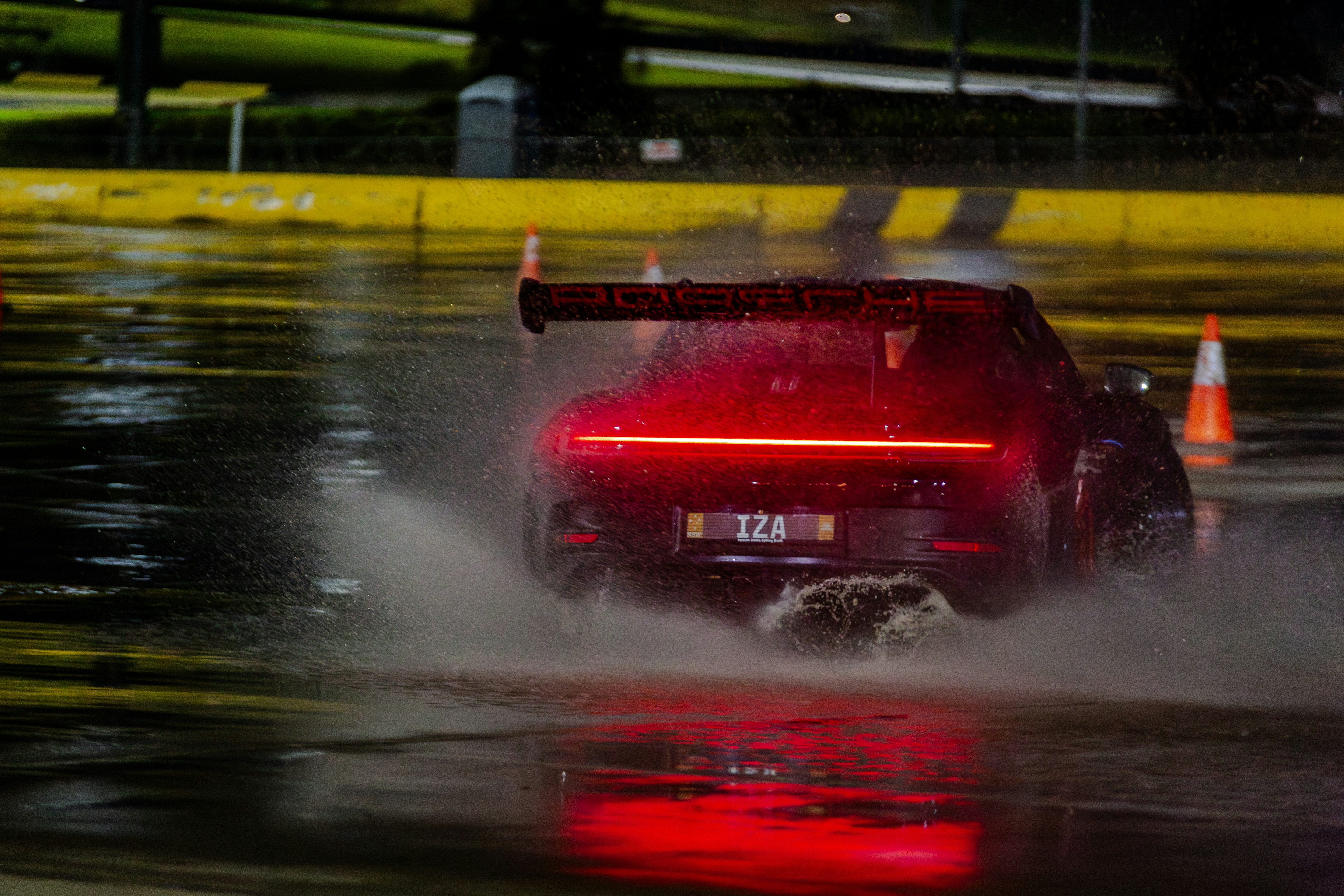 A red sports car speeds through water at night.