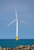 Wind turbine stands tall over the ocean.