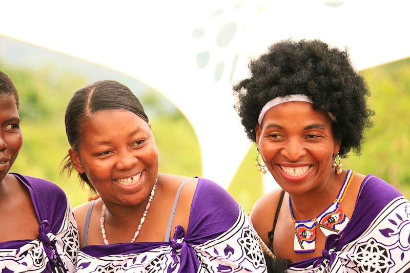Smiling women in traditional african outfits are pictured.