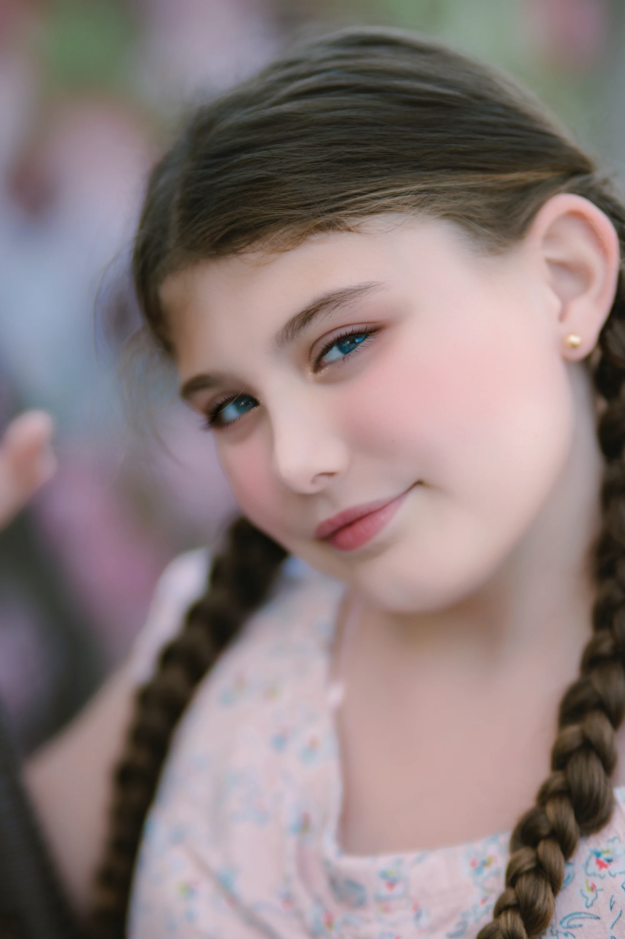 A young girl with braided hair smiling directly at the camera.