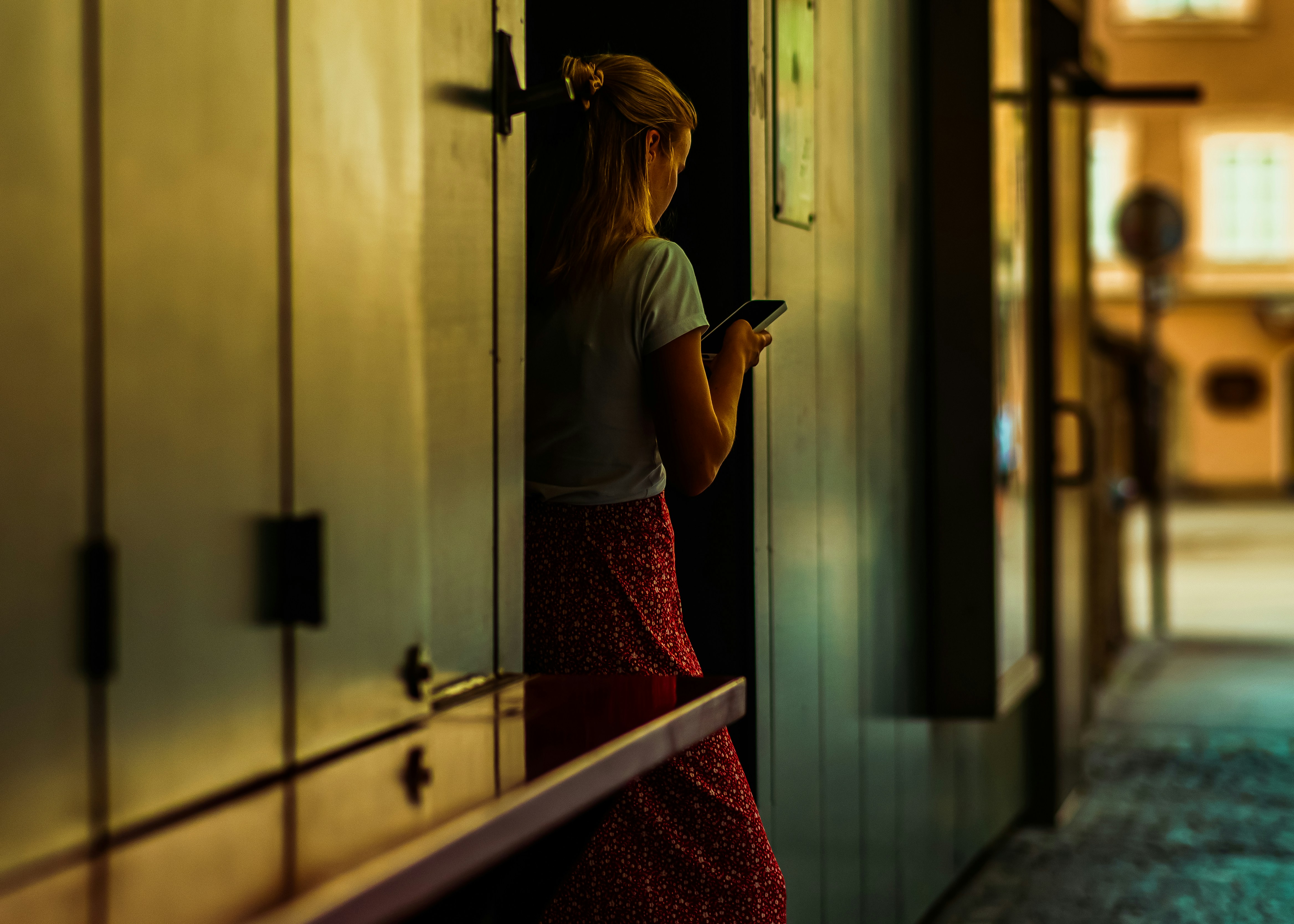 A woman is texting while standing indoors.