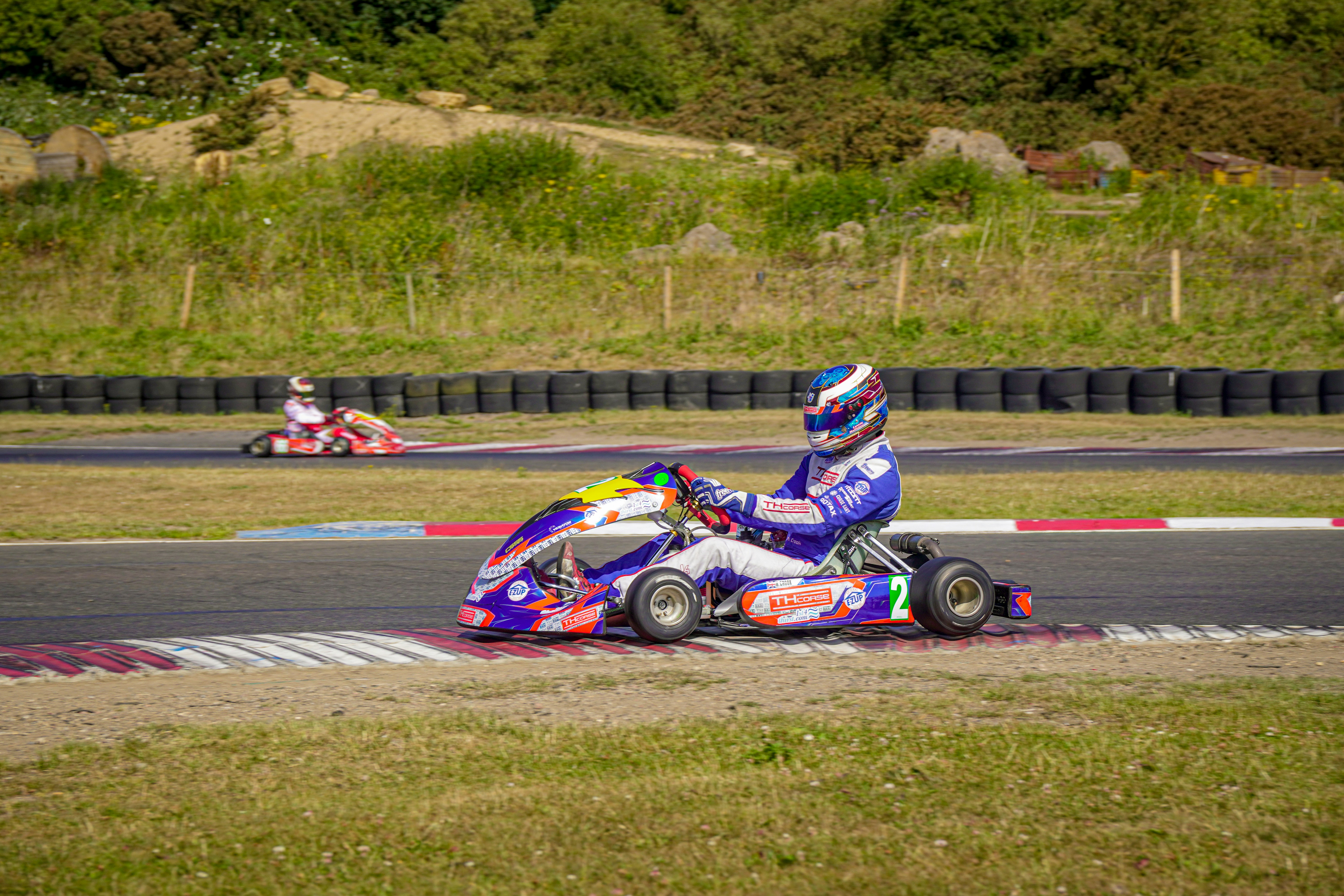 Two go-karts racing on a track with grassy banks.