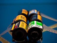 Film rolls are stacked on a reflective, blue surface.