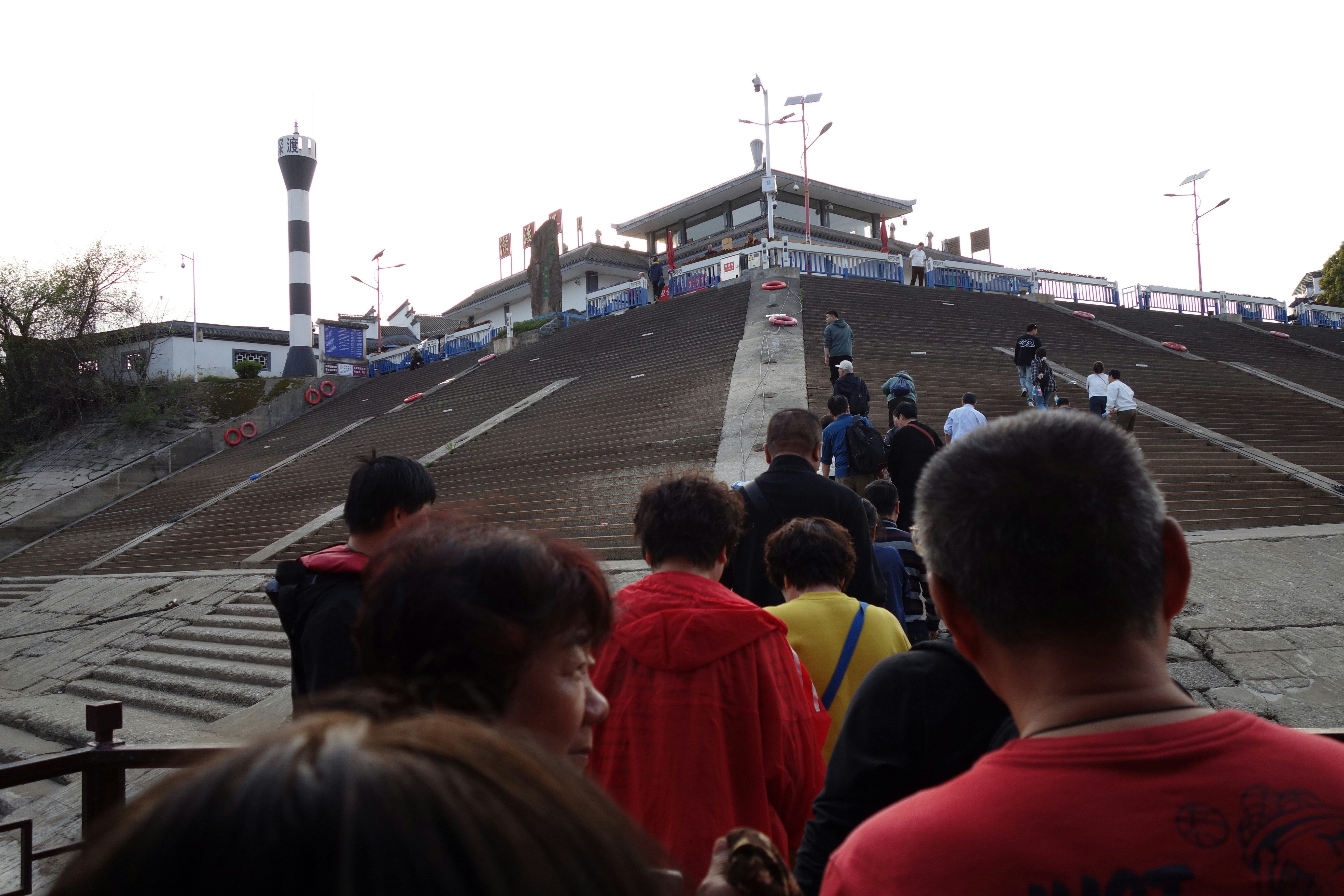 People ascend a long staircase towards a building.