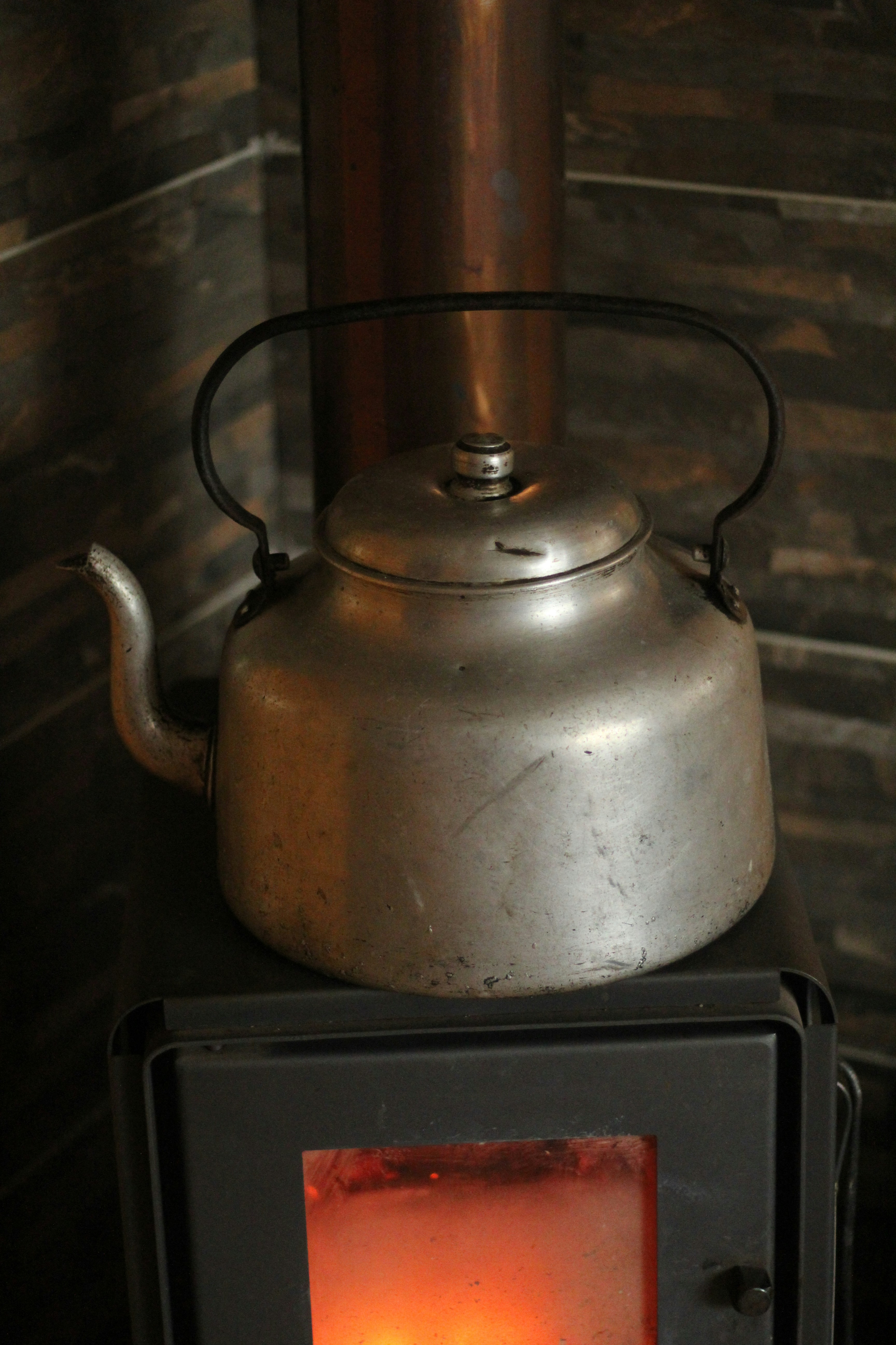 A kettle sits on top of a lit stove.