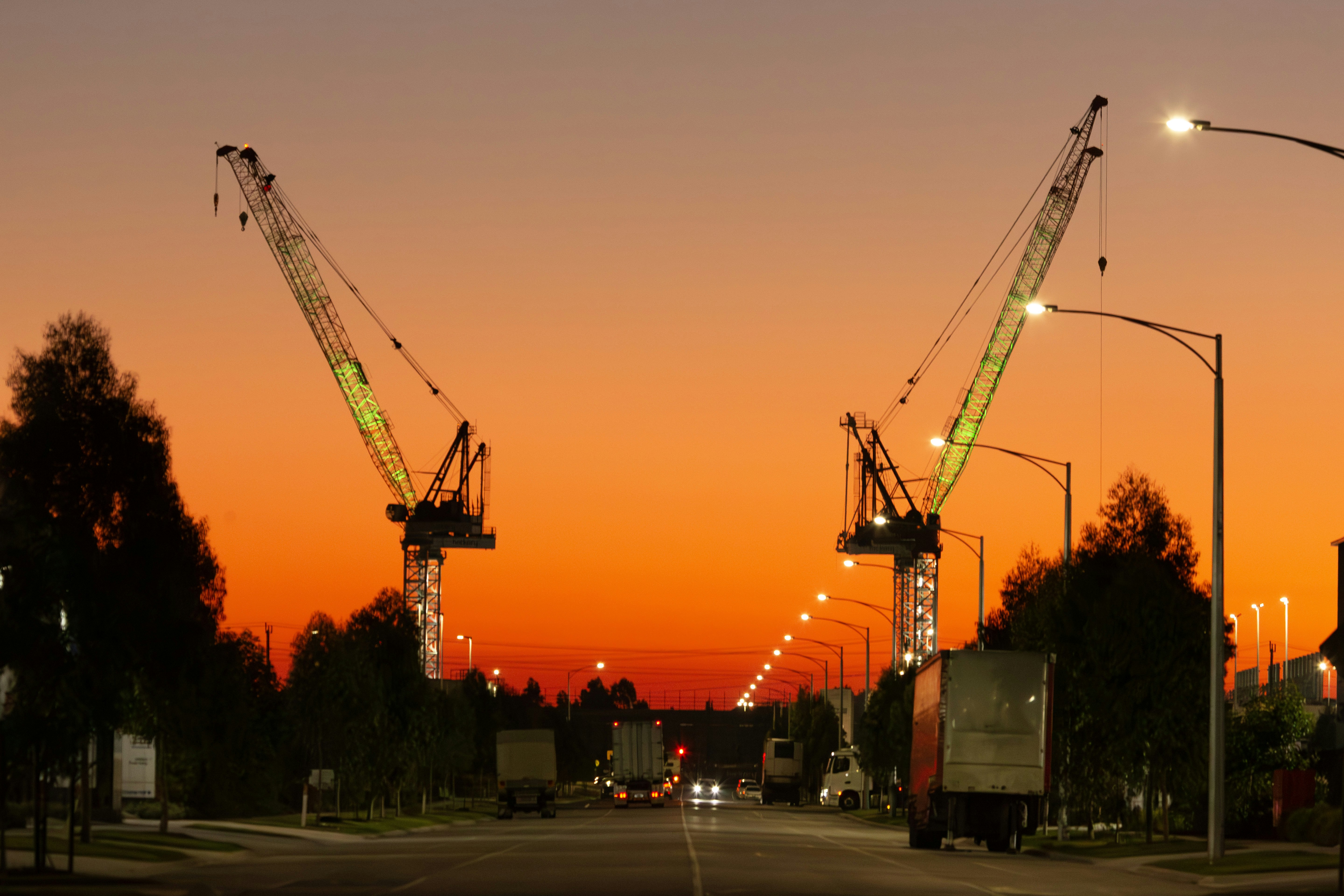Two cranes stand silhouetted against a fiery sunset.