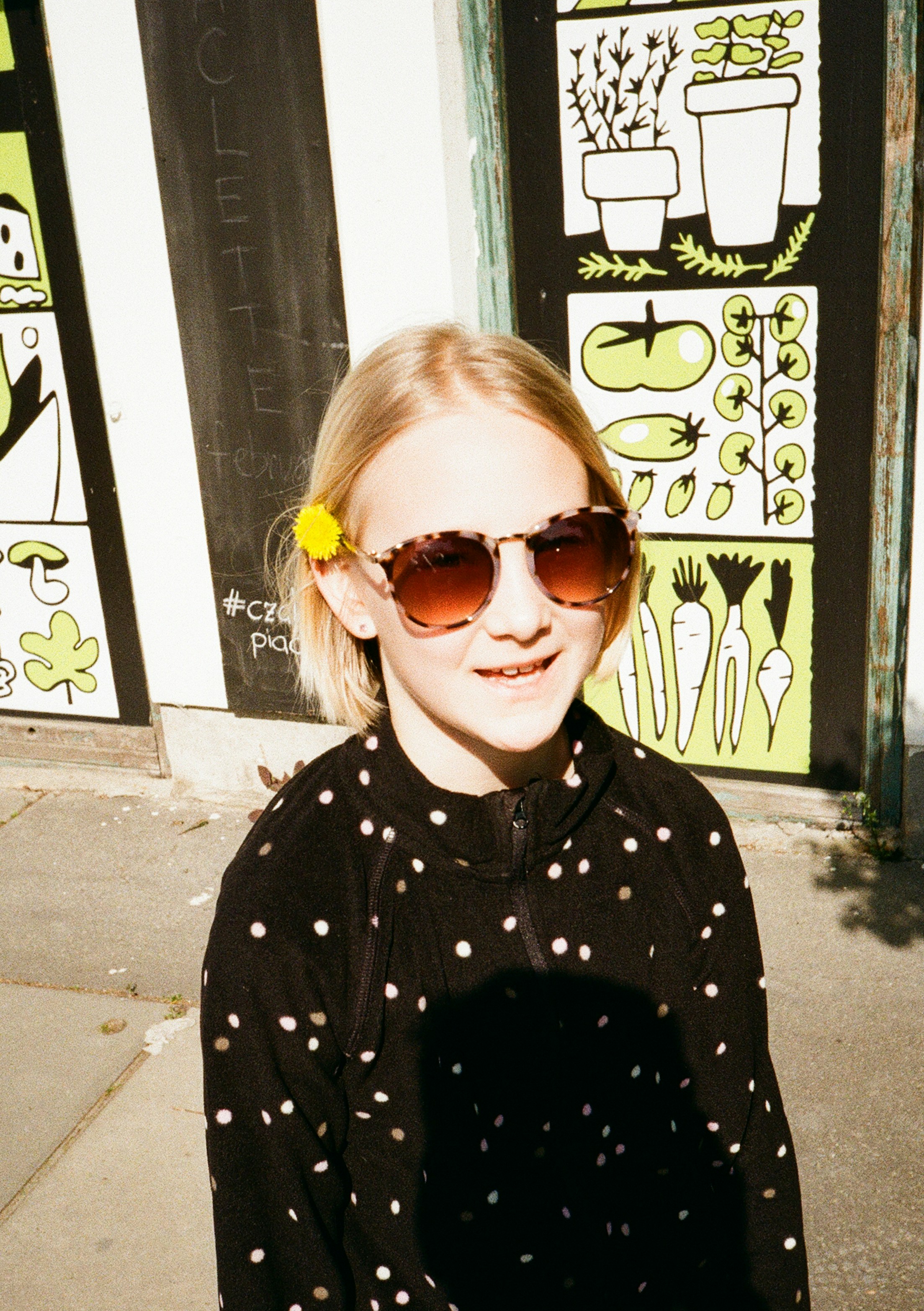 A girl smiles while wearing sunglasses