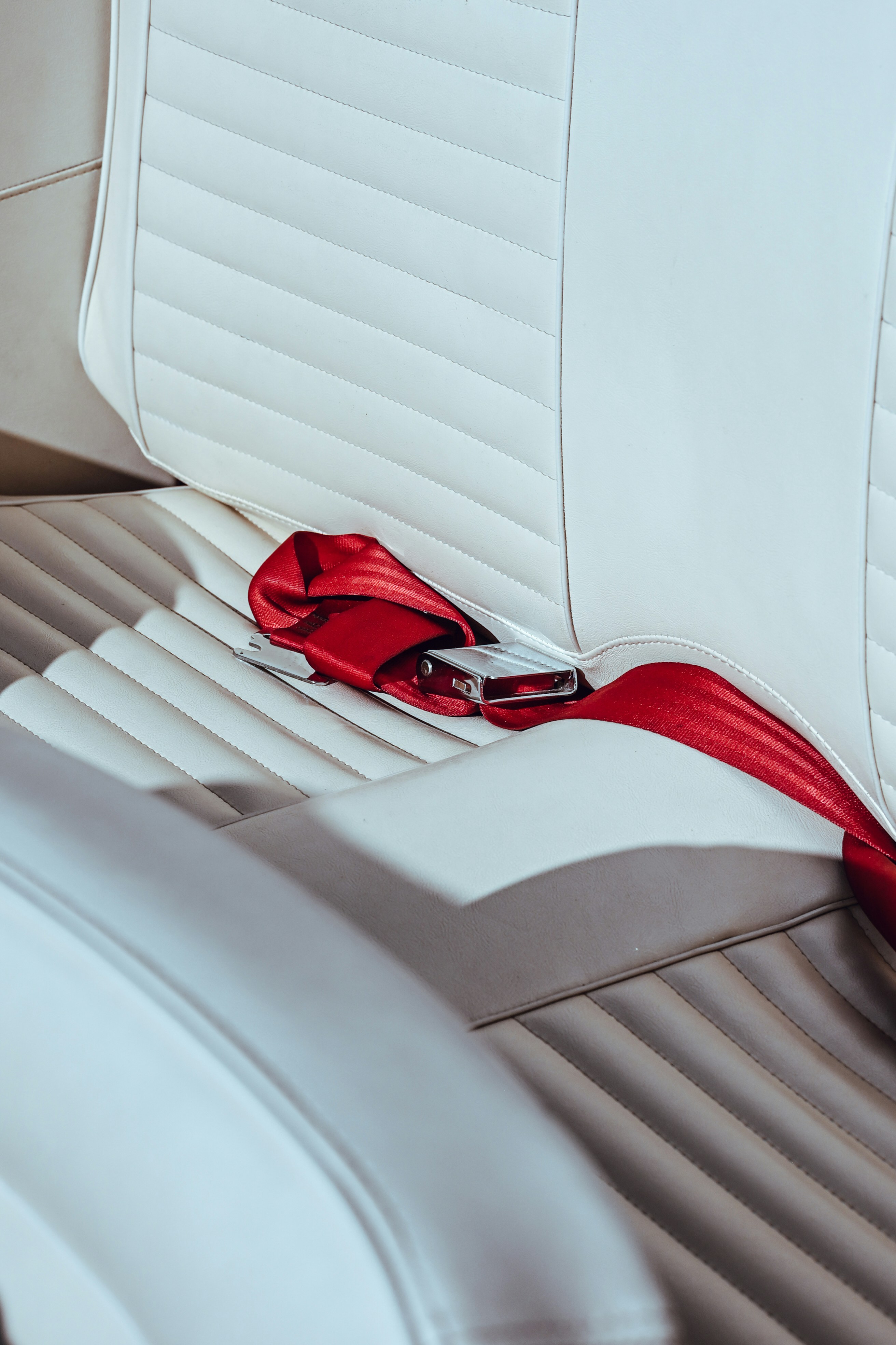 White car seat with red seatbelt.