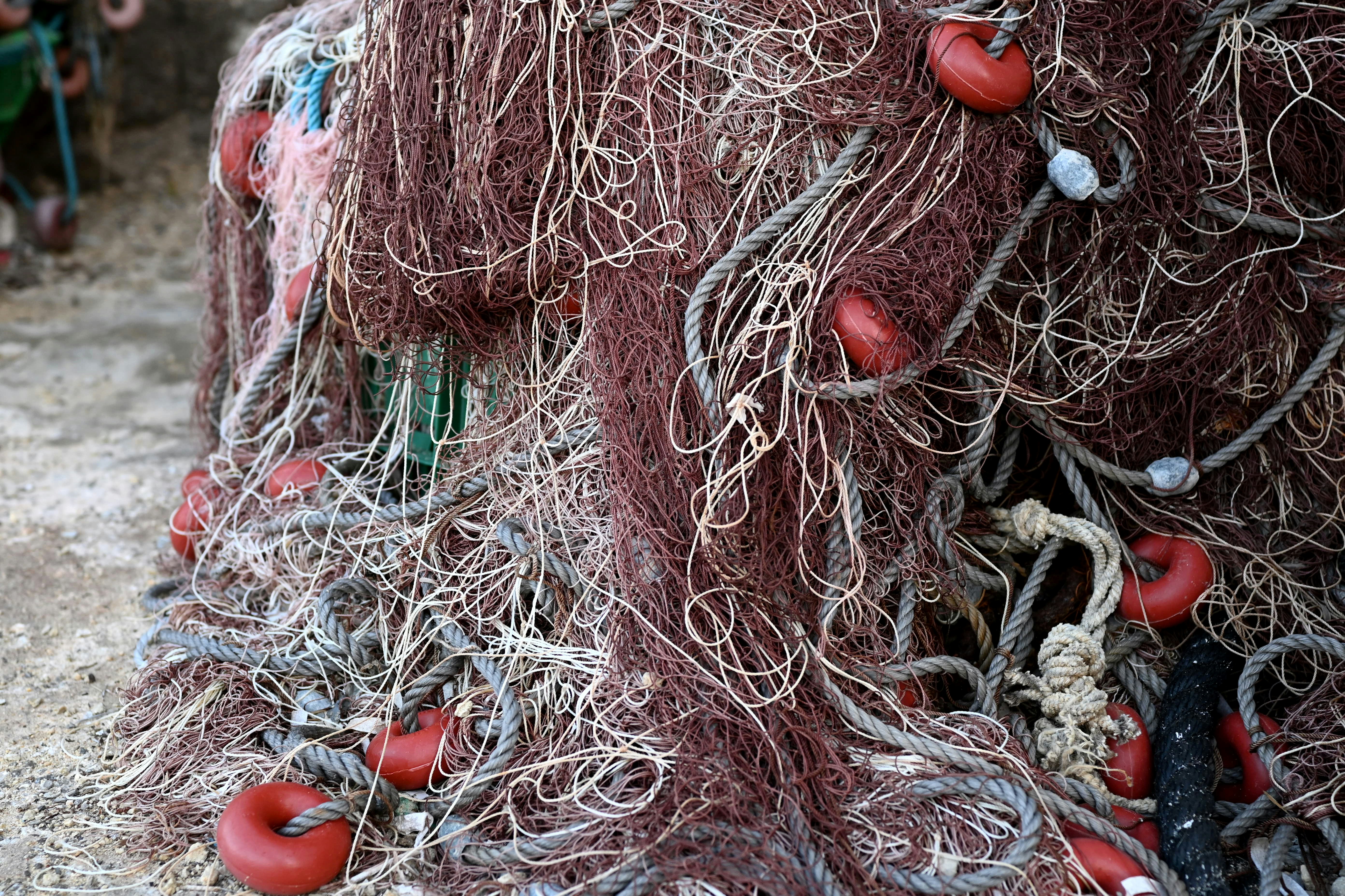 Tangled fishing net with red buoys piled on top.