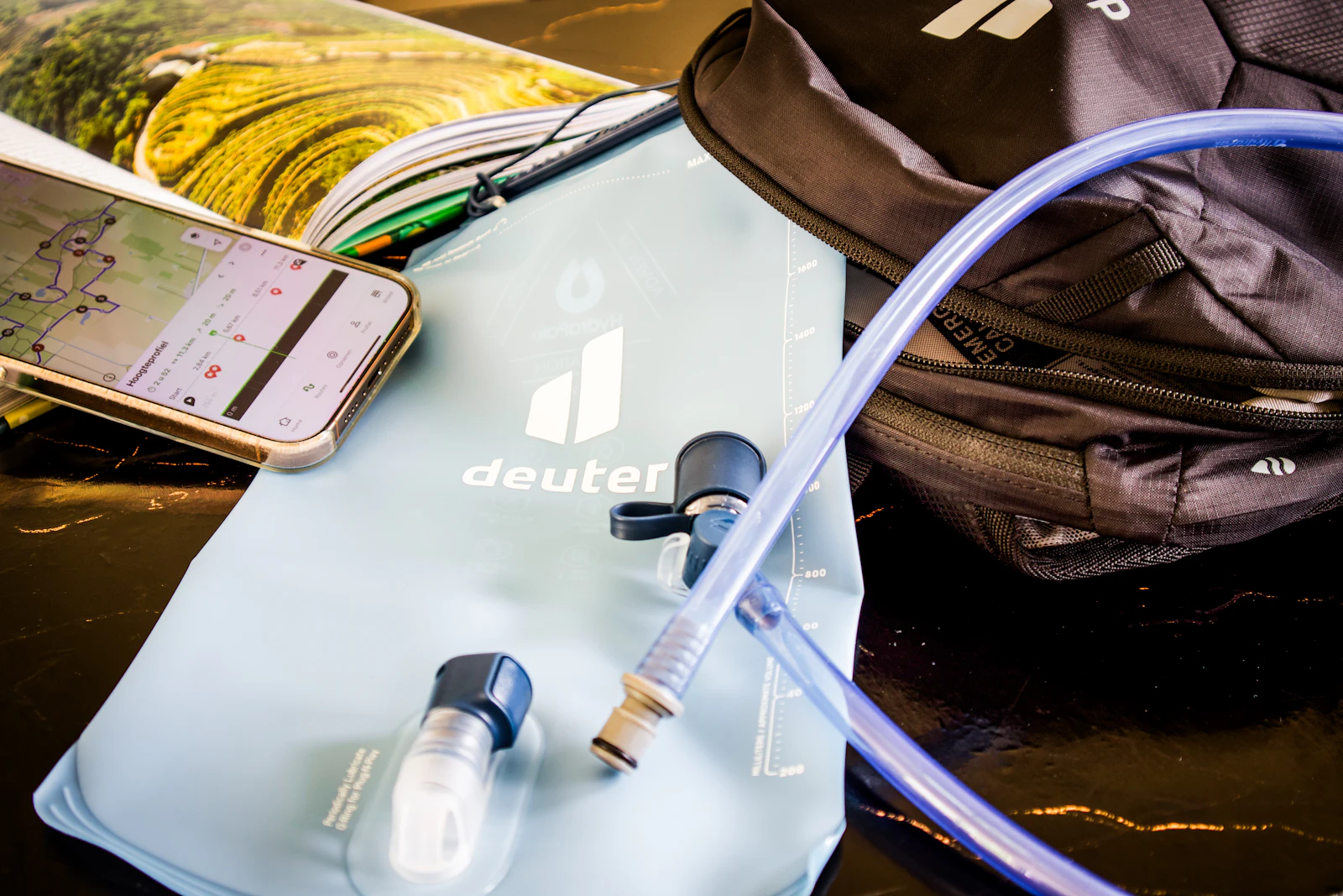 Photograph of A hiking backpack, water bladder and phone displaying a map laid out before departure.