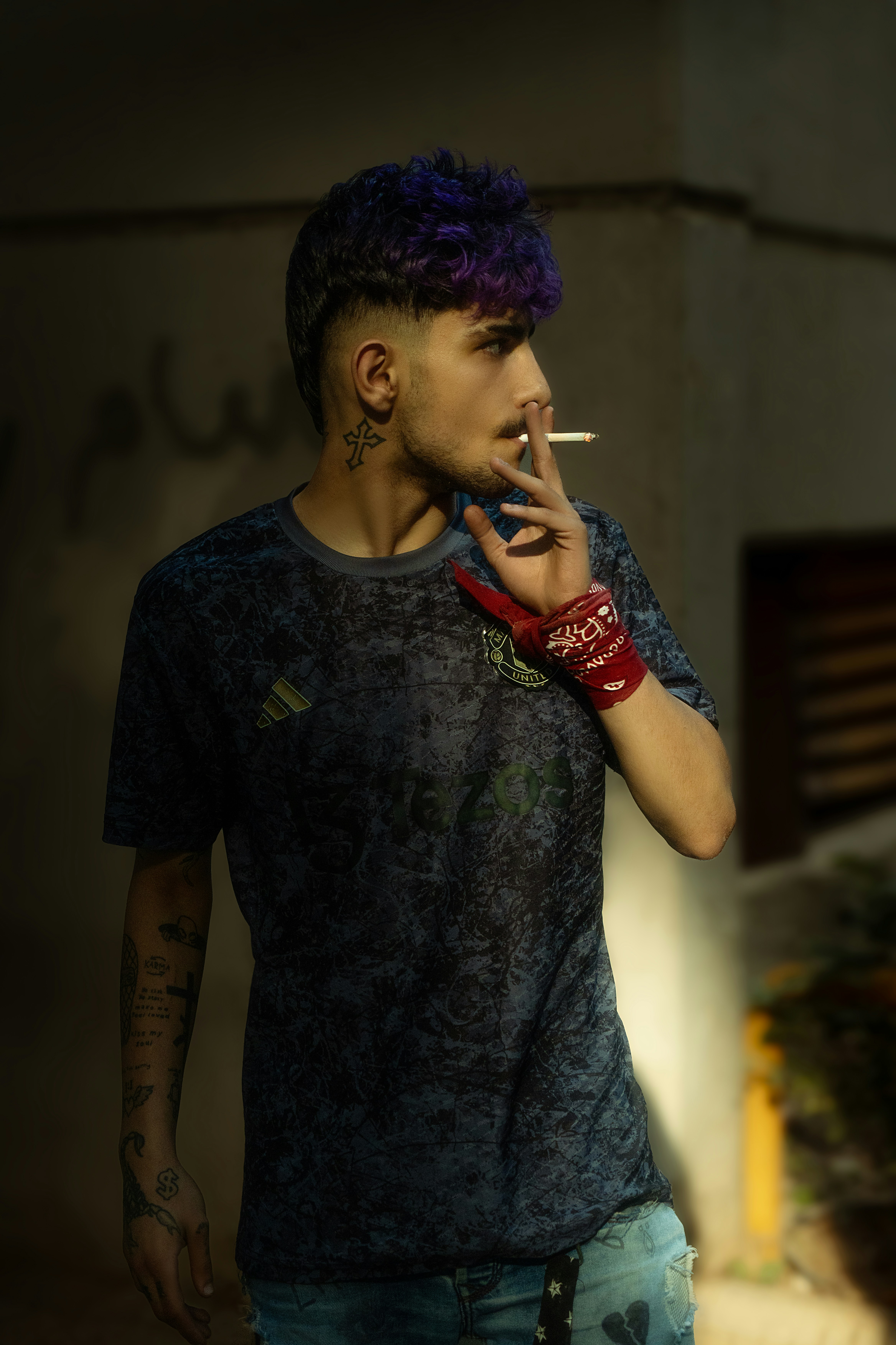 Man with purple hair smokes a cigarette.