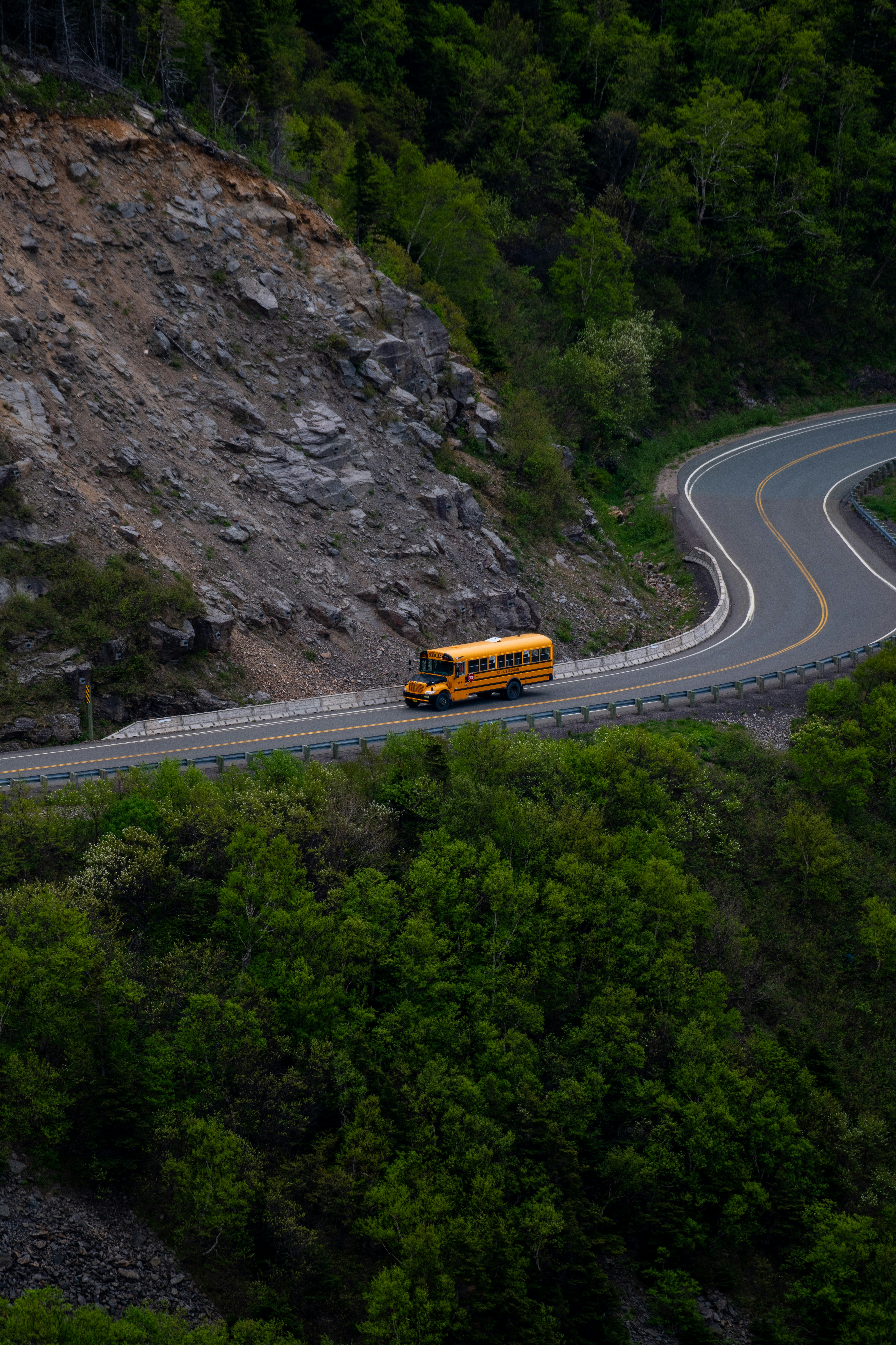 A school bus drives along a winding mountain road.