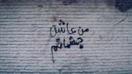 Graffiti in farsi decorates a brick wall.