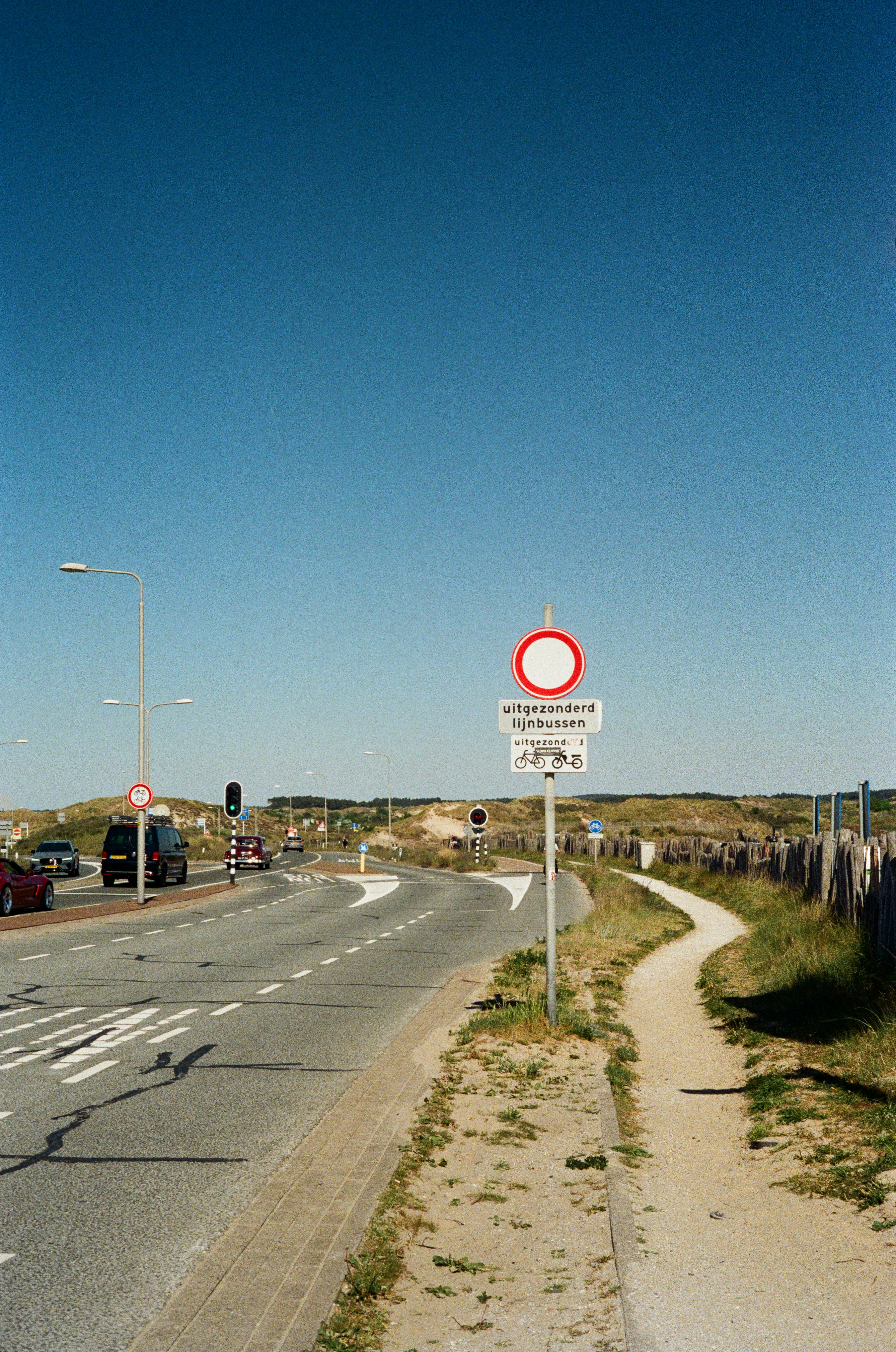 Road with cars, signs, and a clear blue sky.
