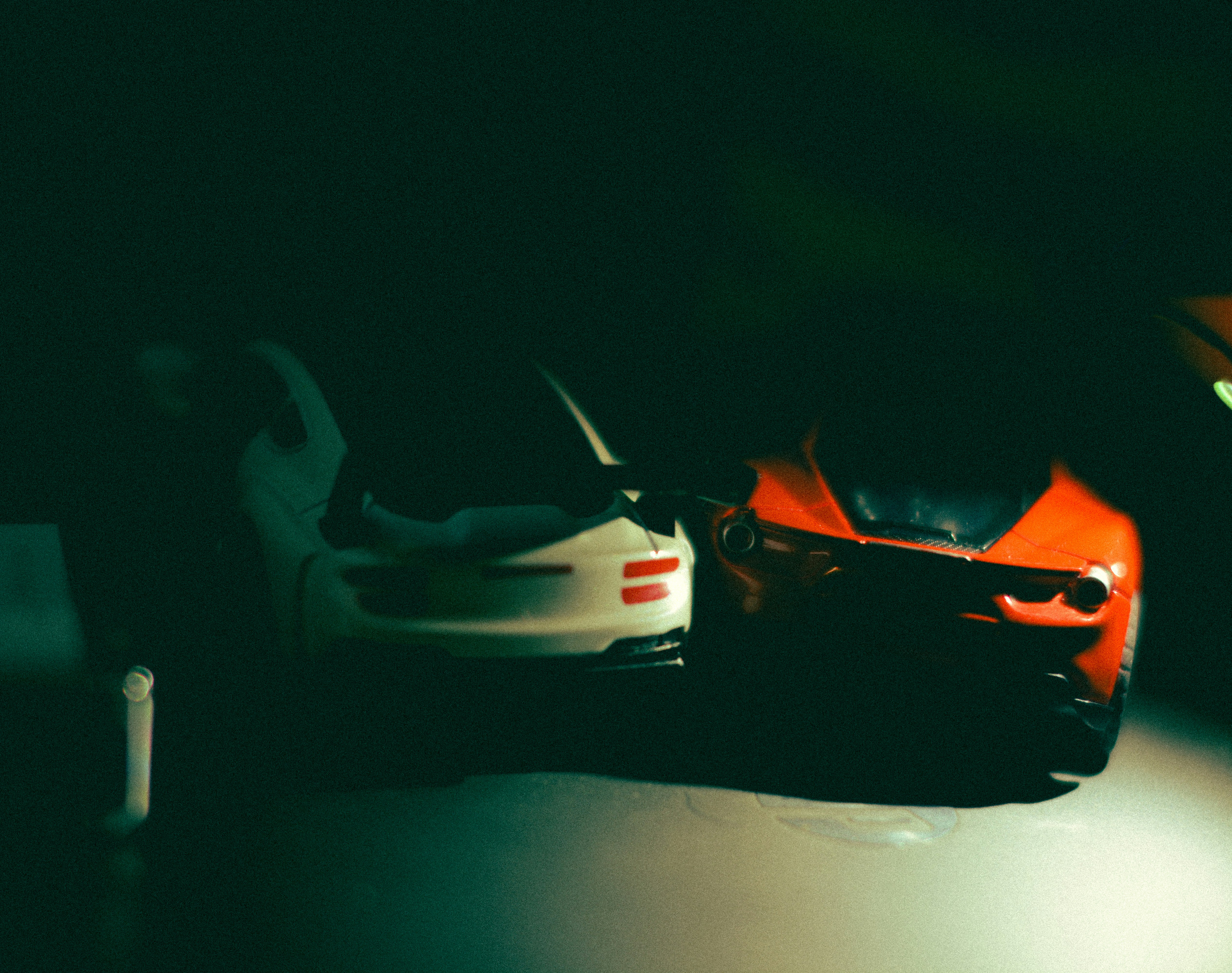 Dois carrinhos de brinquedo ficam lado a lado no escuro.