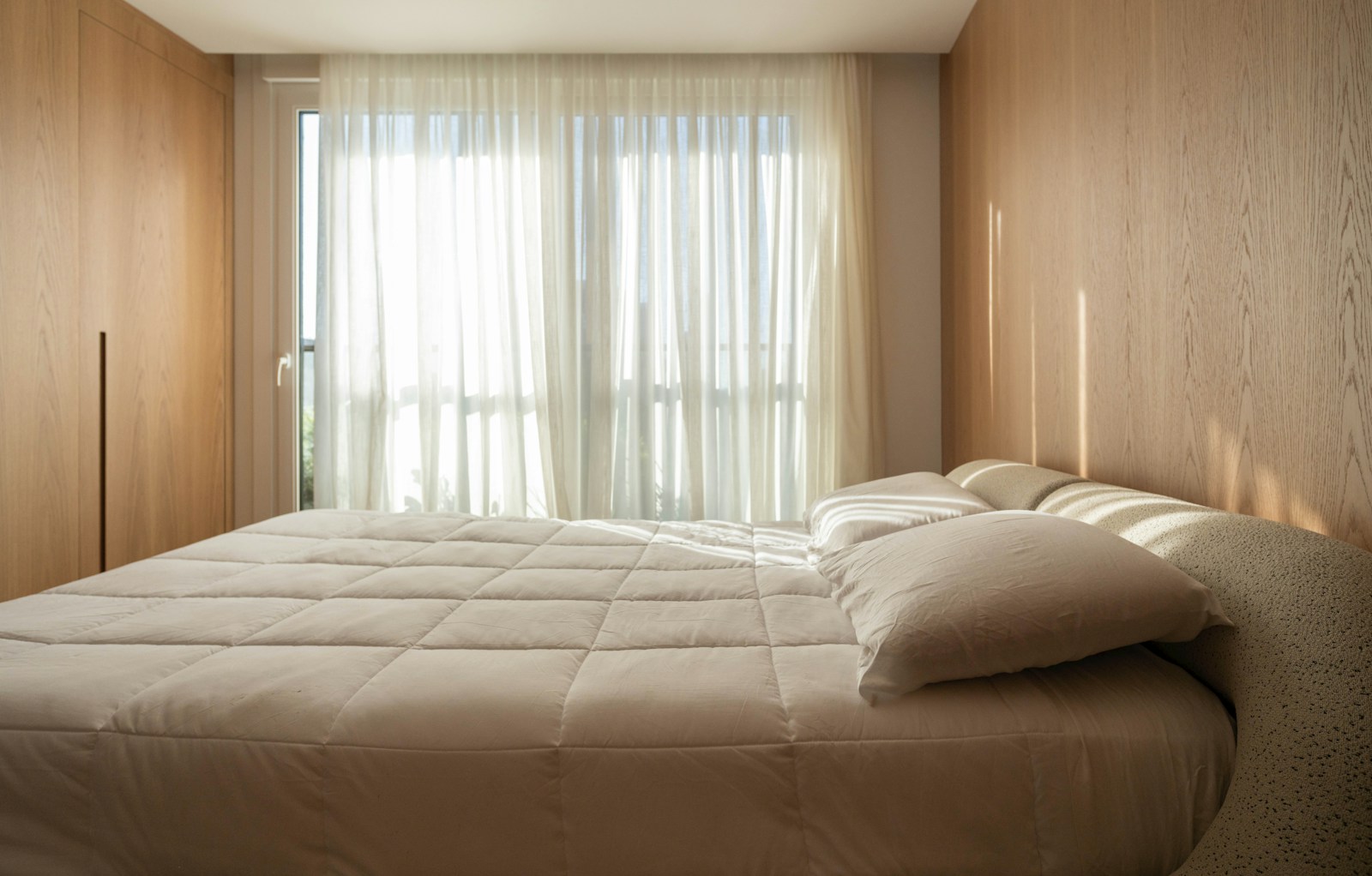 500 sq ft studio bedroom zone with queen bed sheer curtains and wood walls