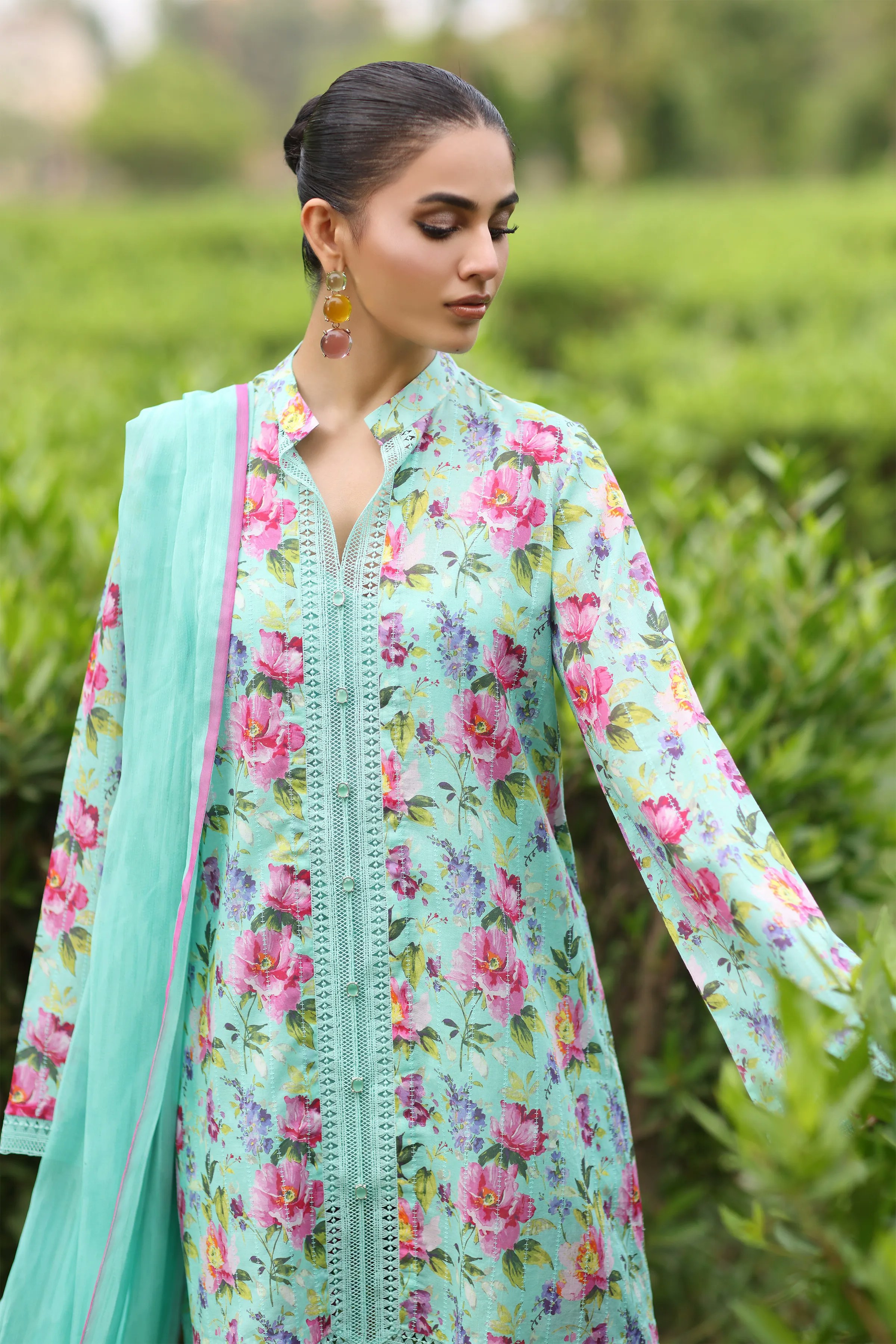 Woman models a floral print outfit in a garden.
