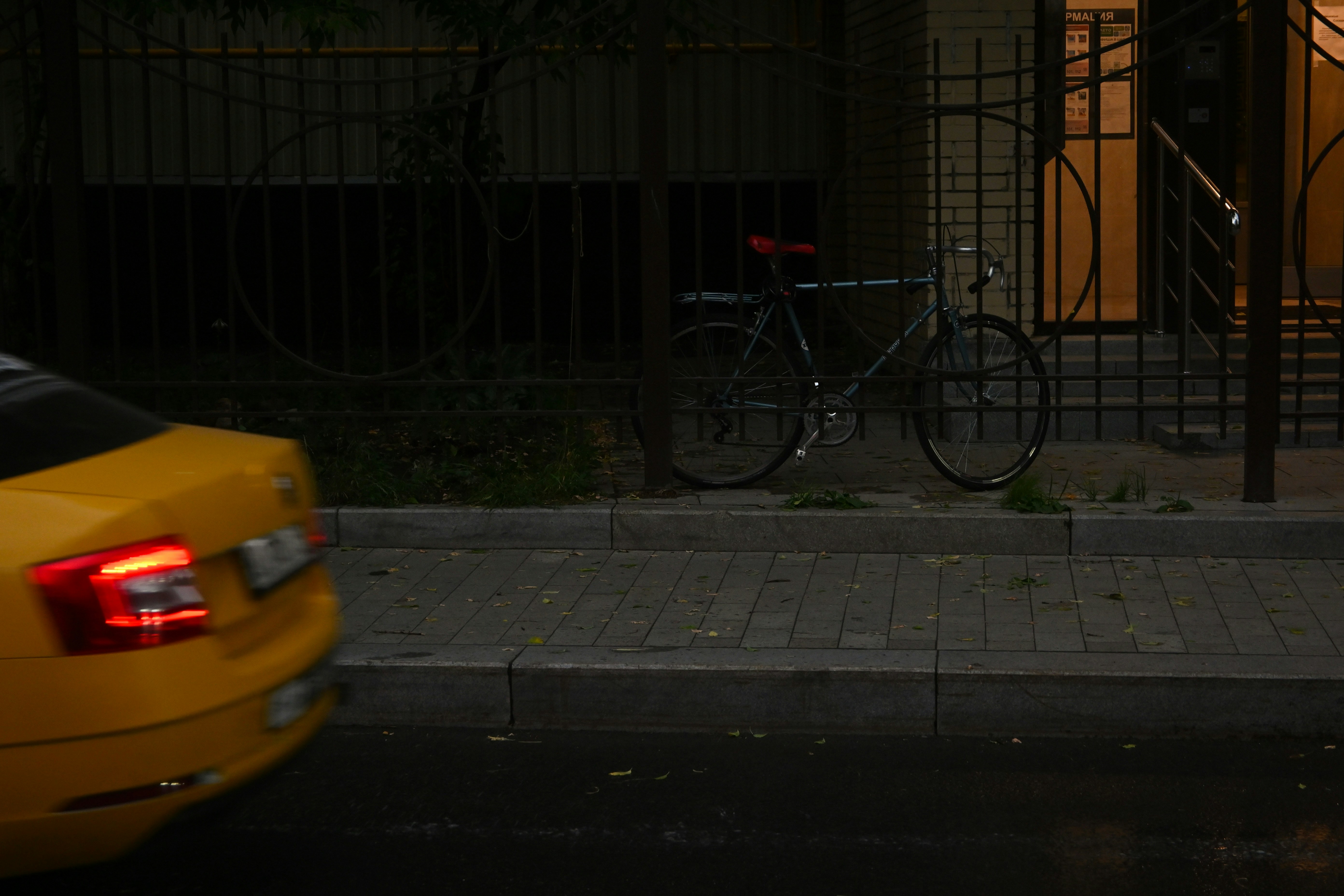 A bicycle stands by a building at night.