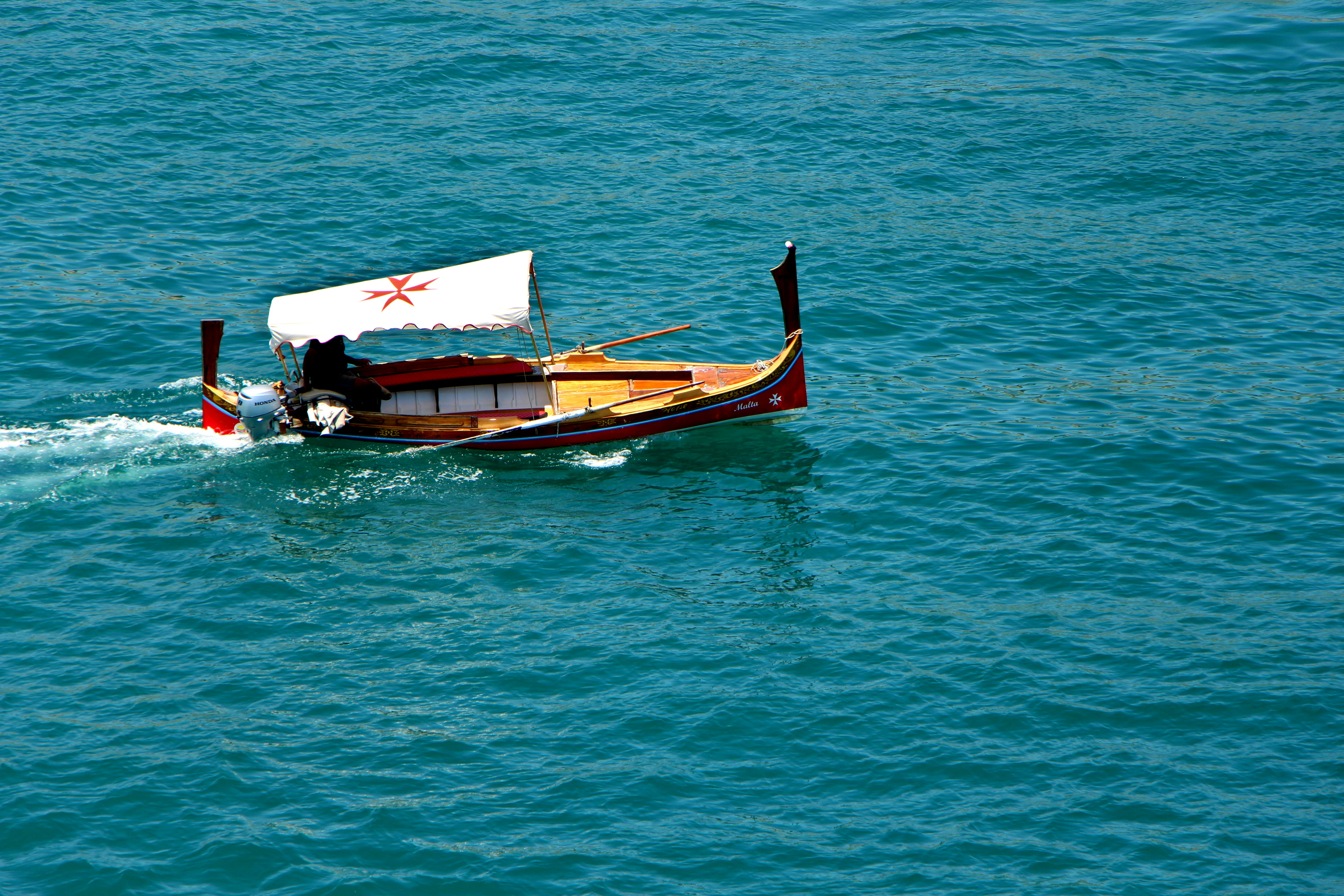 A colorful boat sails on the blue sea.