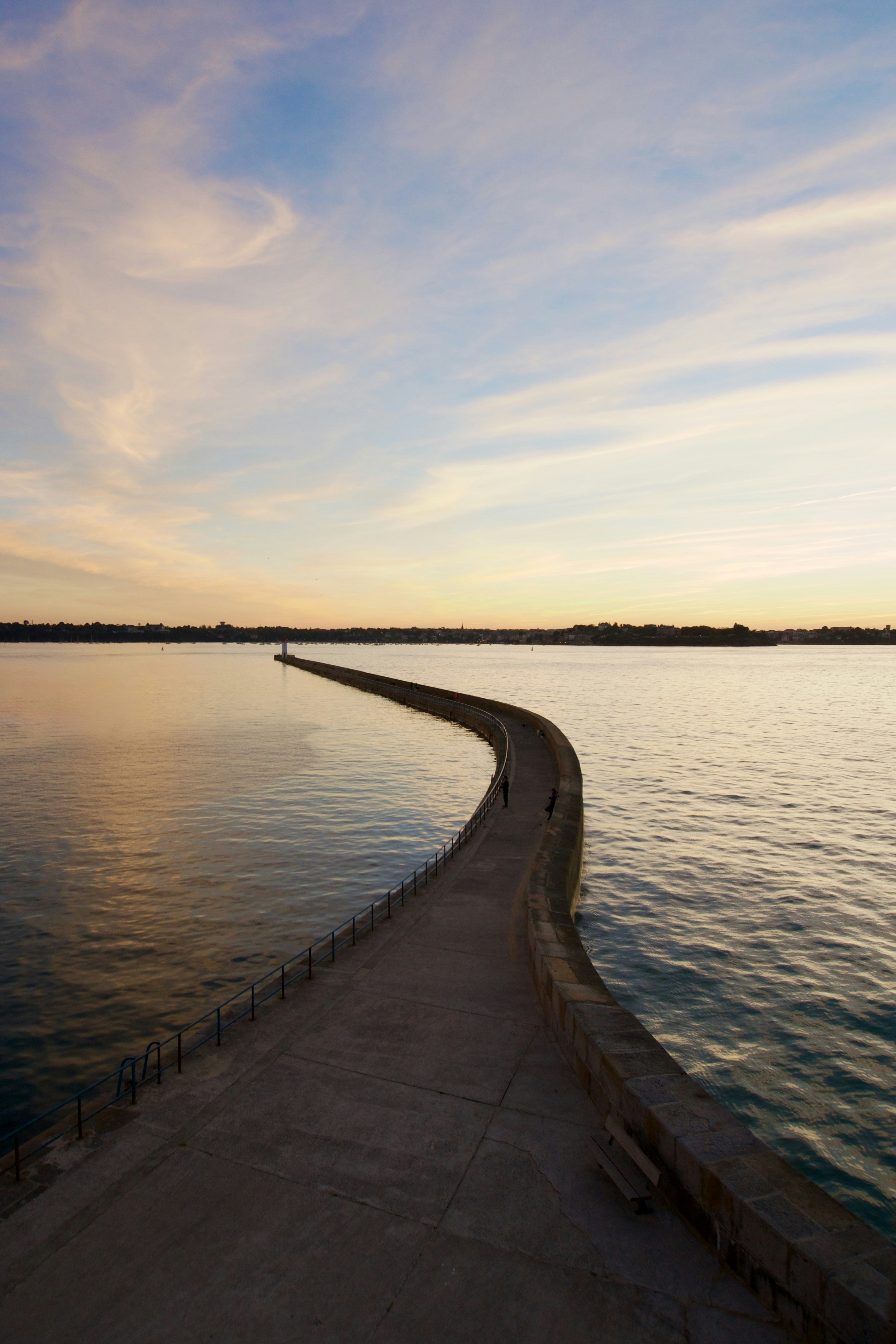 A pier stretches into calming water at sunset
