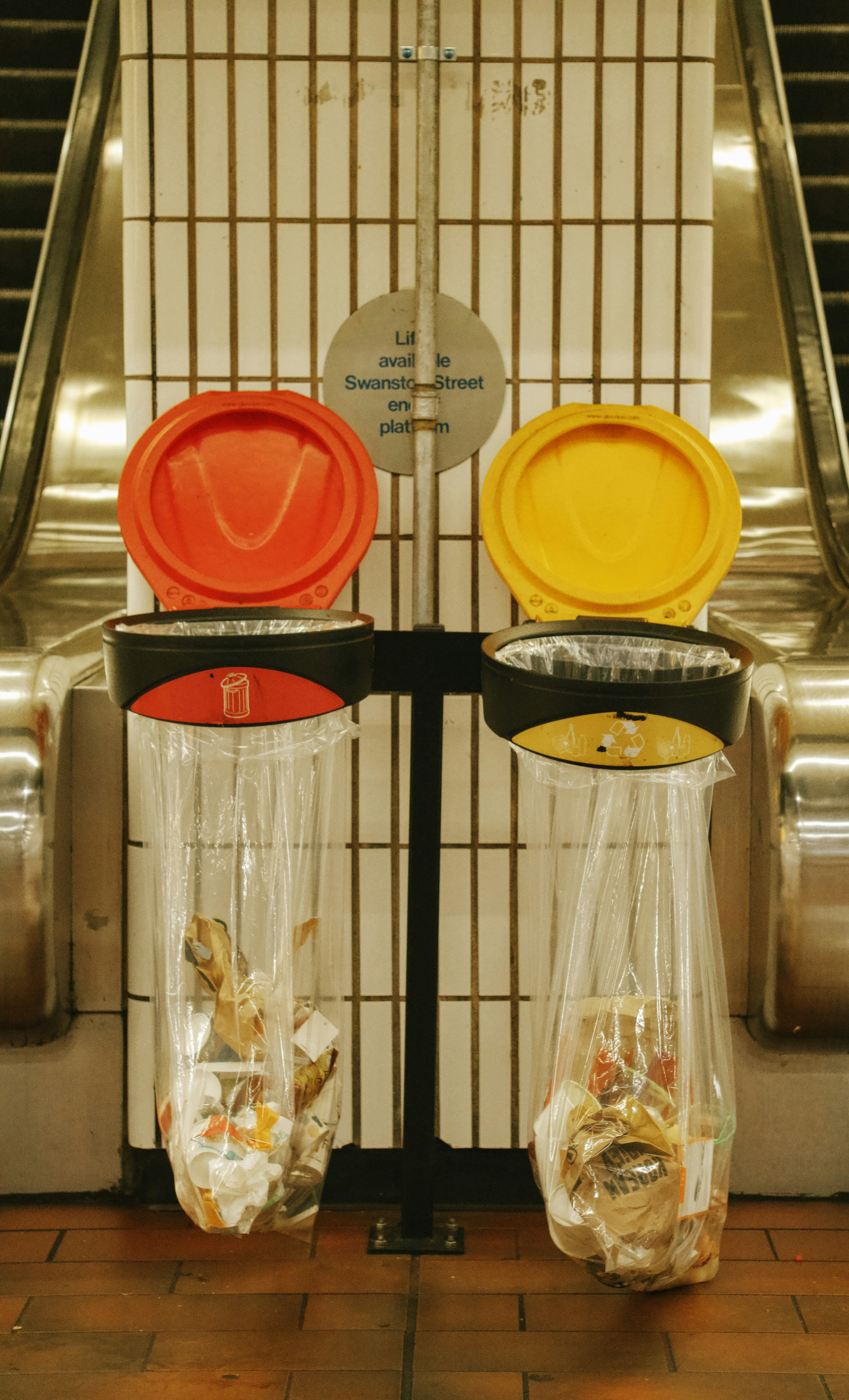 Two colorful trash cans at a subway station.