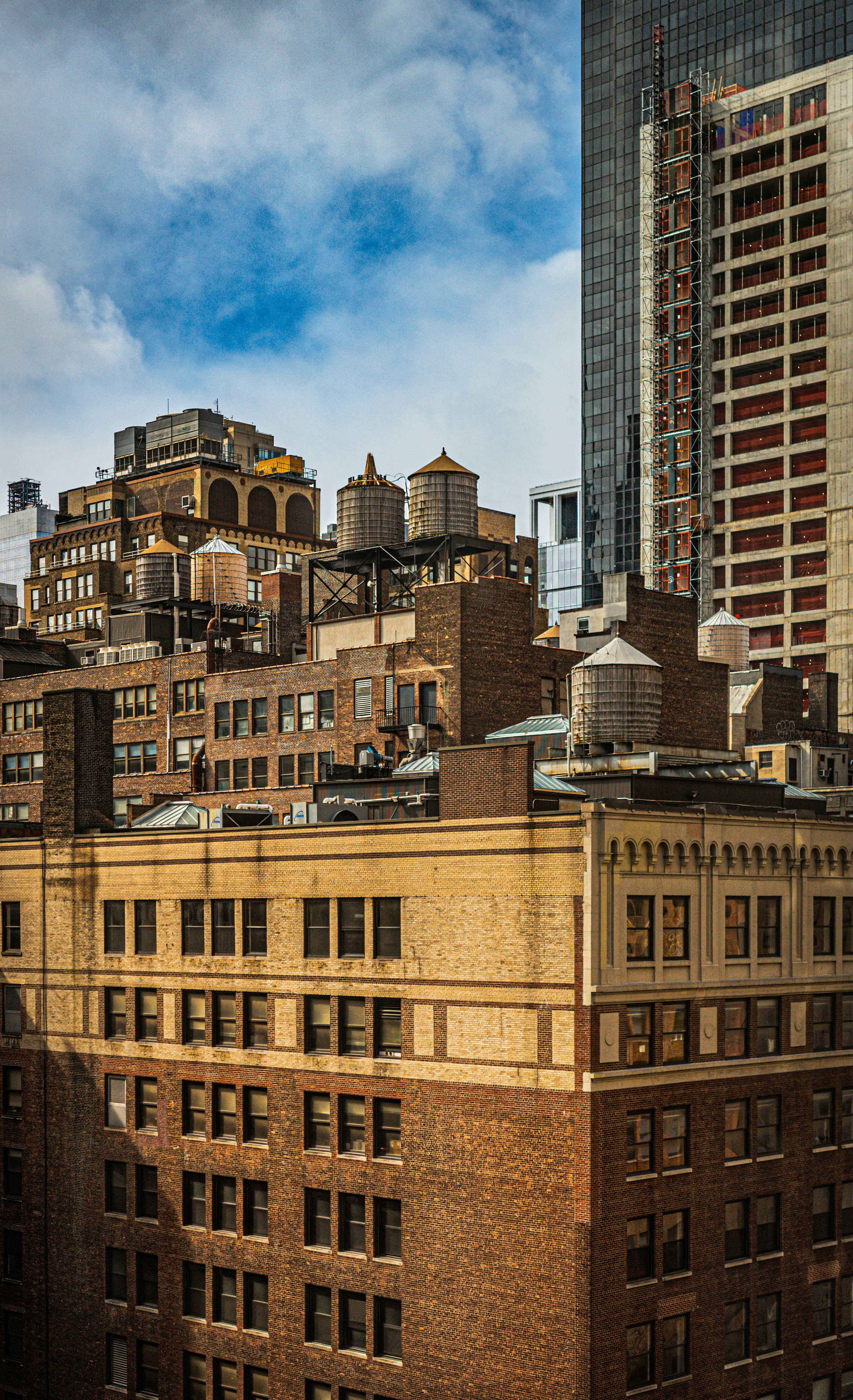 City rooftops with water towers under a blue sky.