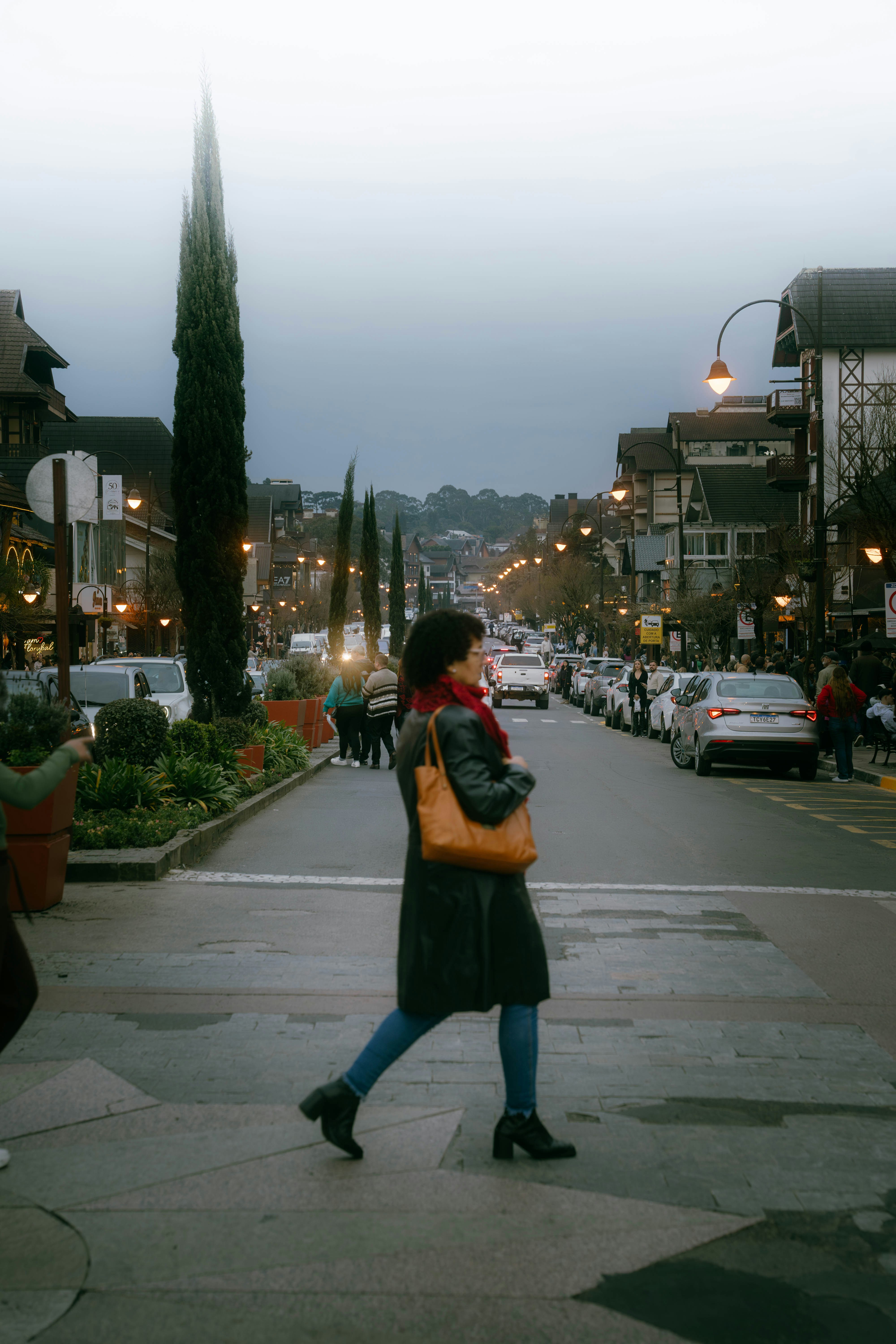 A woman walks across a street in a town.