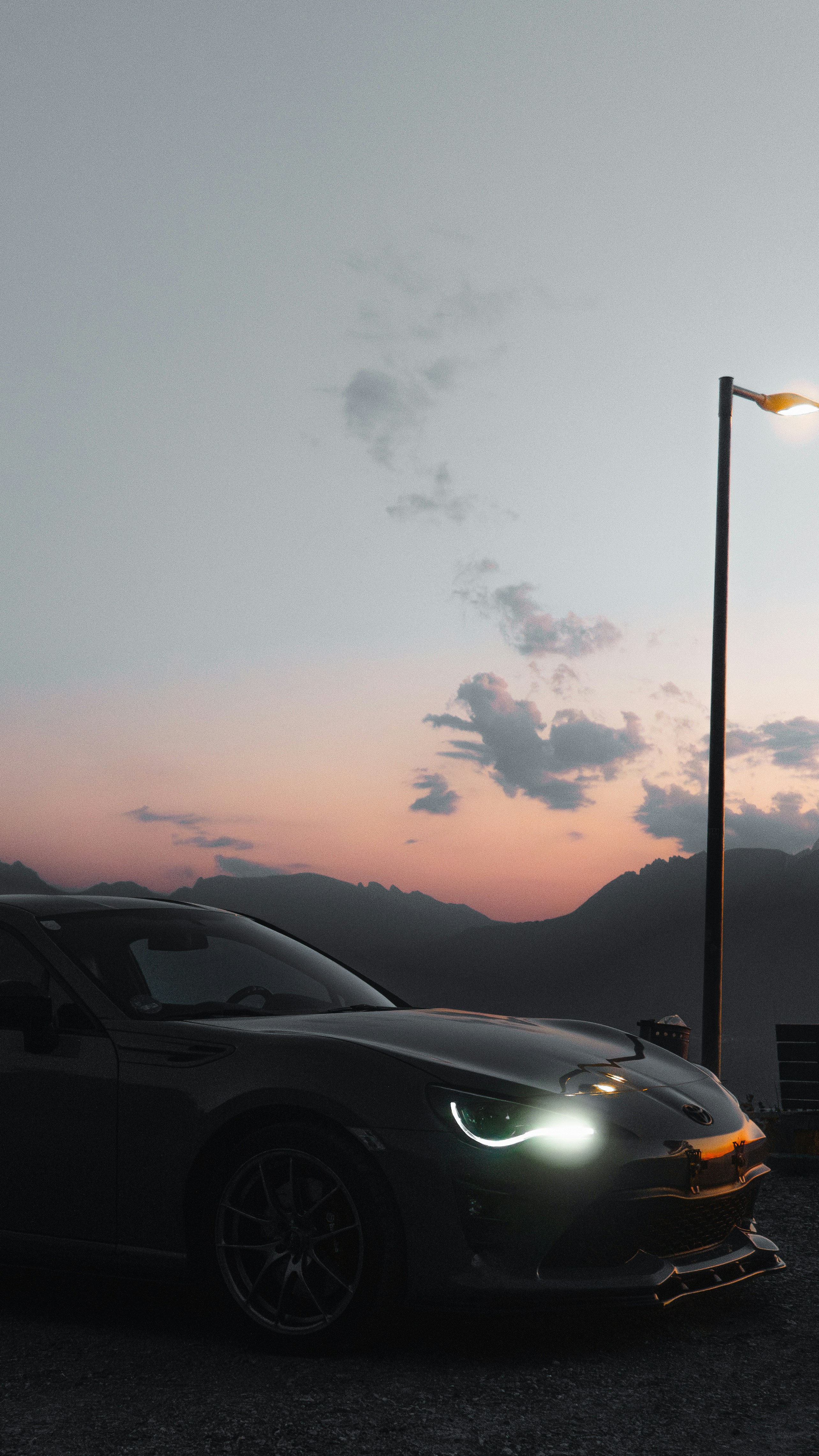 A car parked at sunset with mountains.