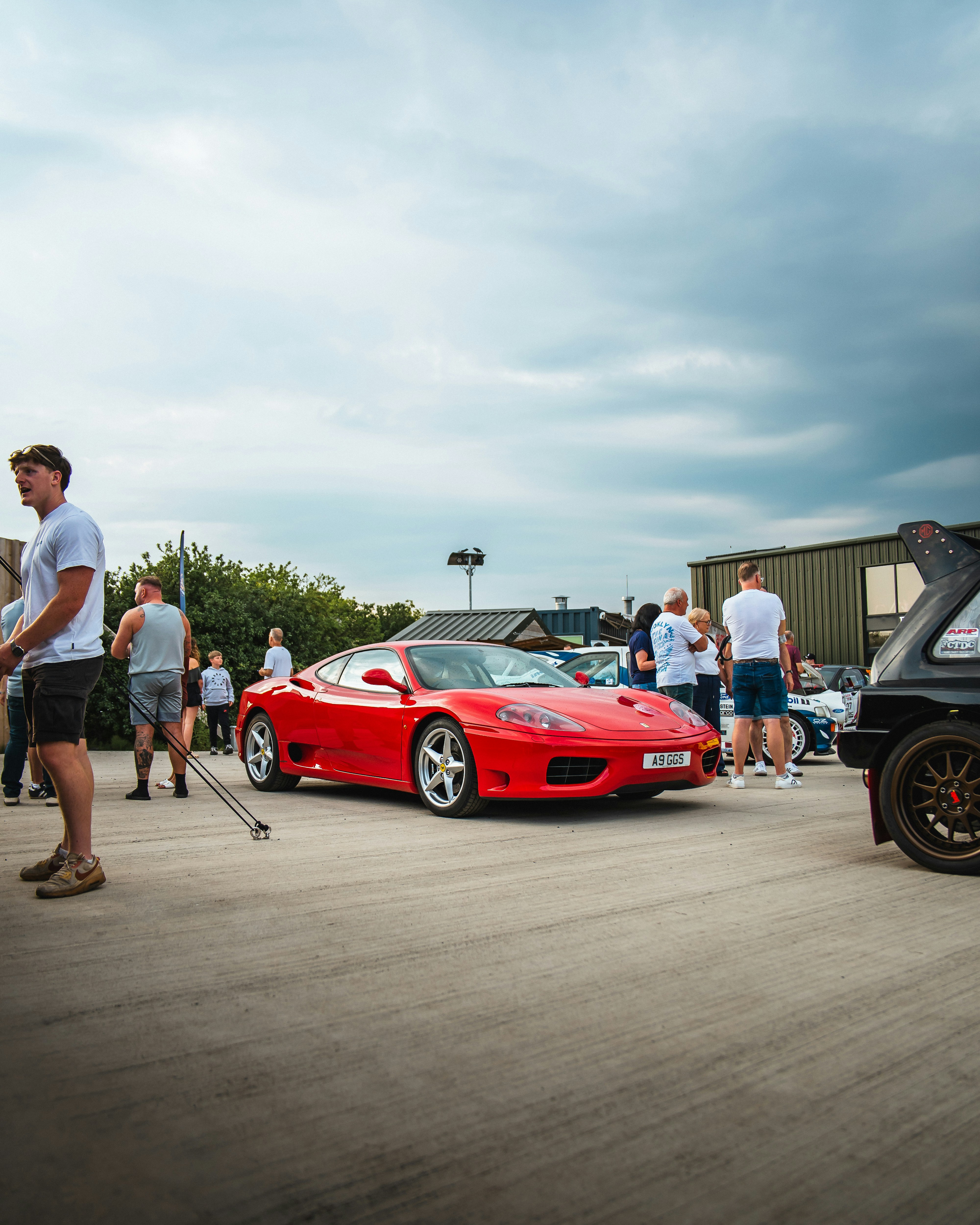 A red ferrari is parked near a crowd.