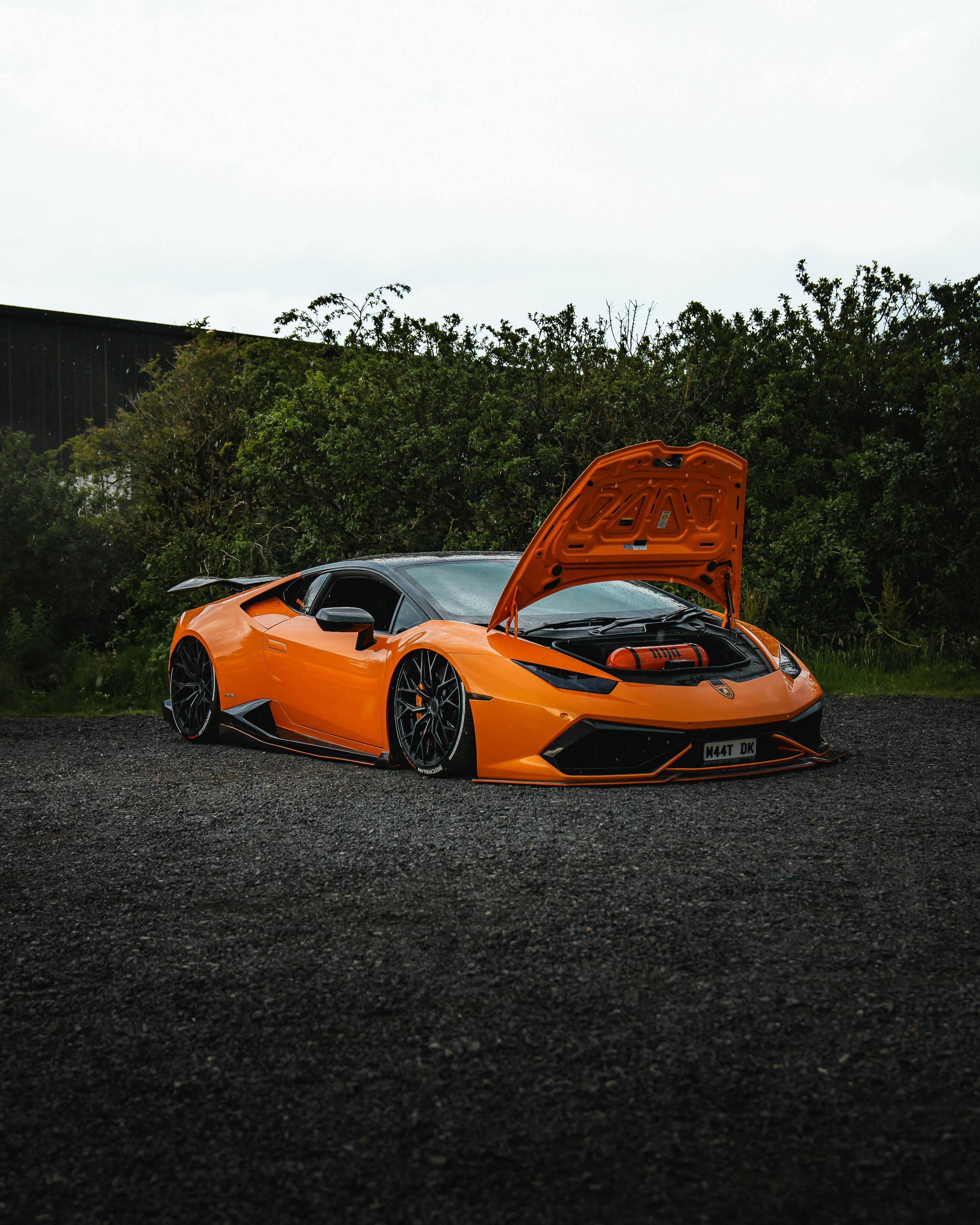 An orange lamborghini with its hood up.