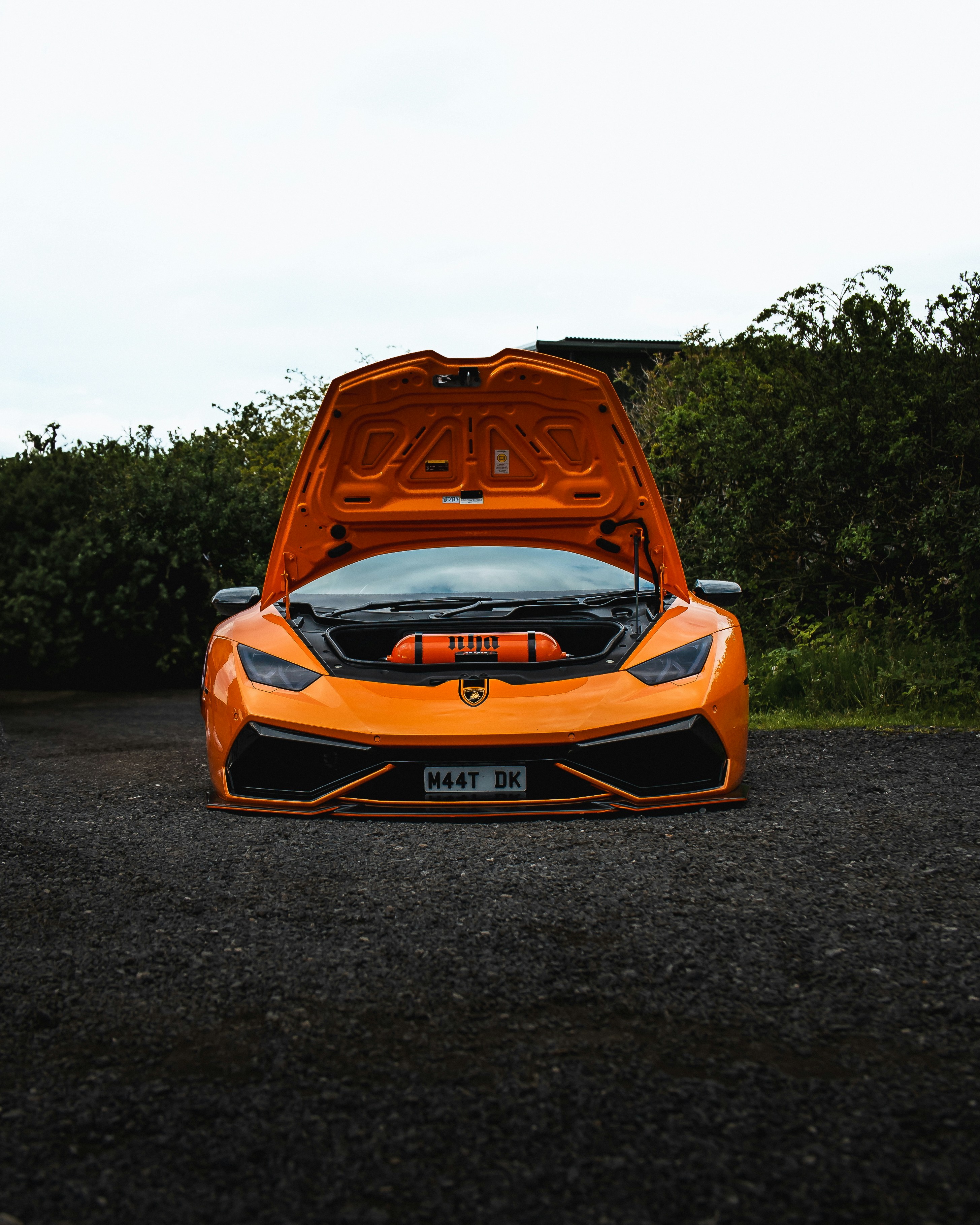 Orange lamborghini with its hood open.