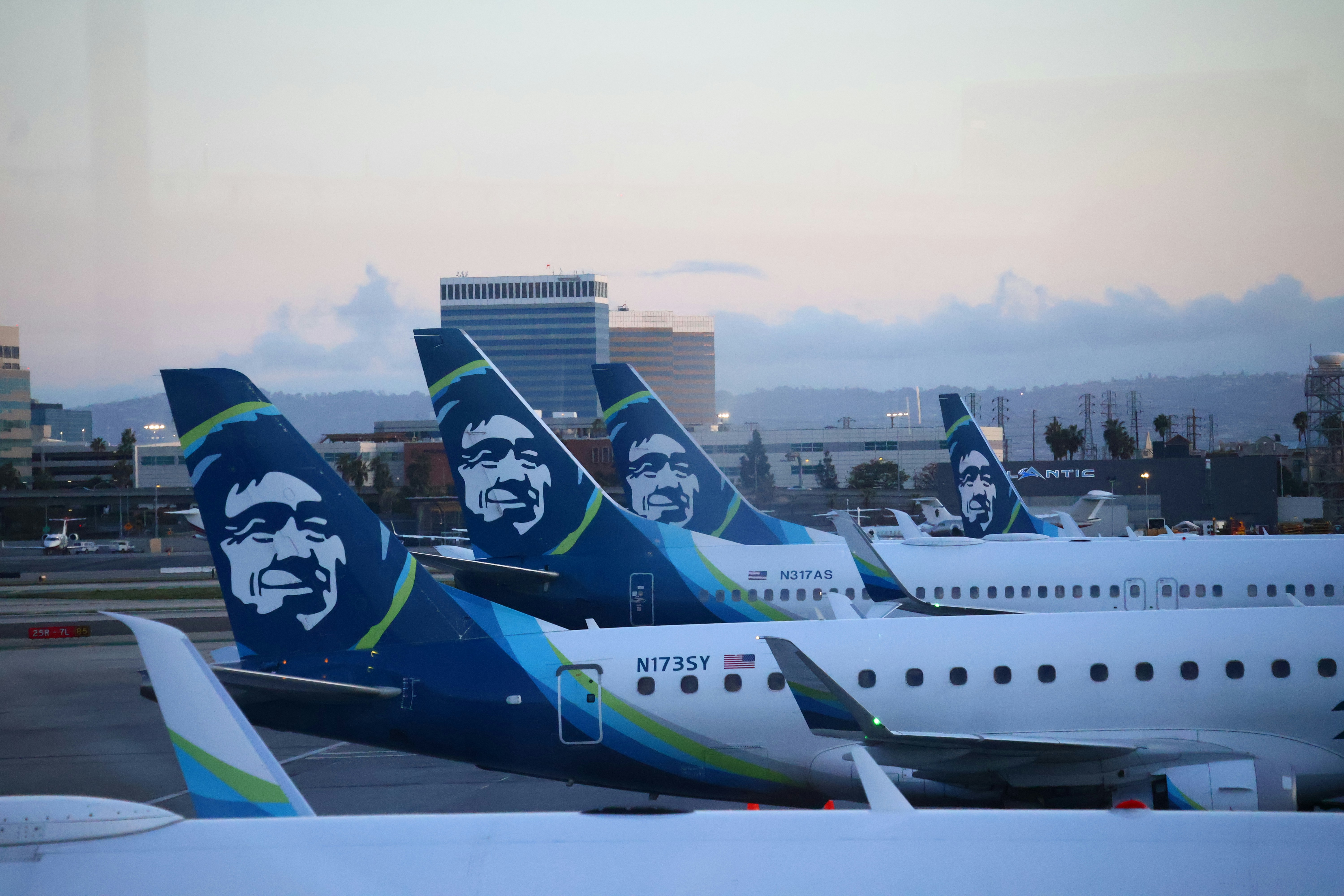 Alaska airlines planes are lined up on the tarmac.