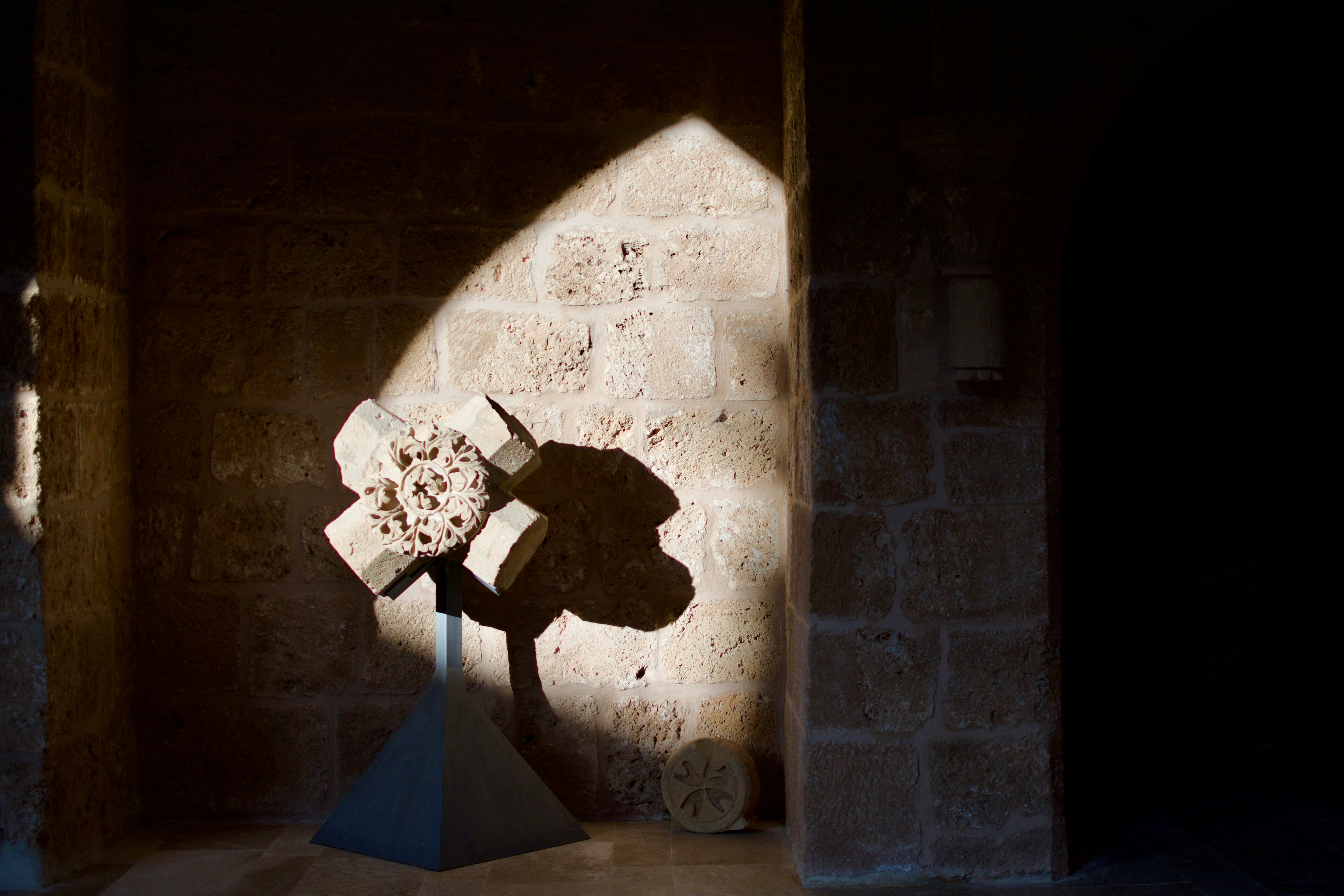 Stone cross sculpture casts dramatic shadows.