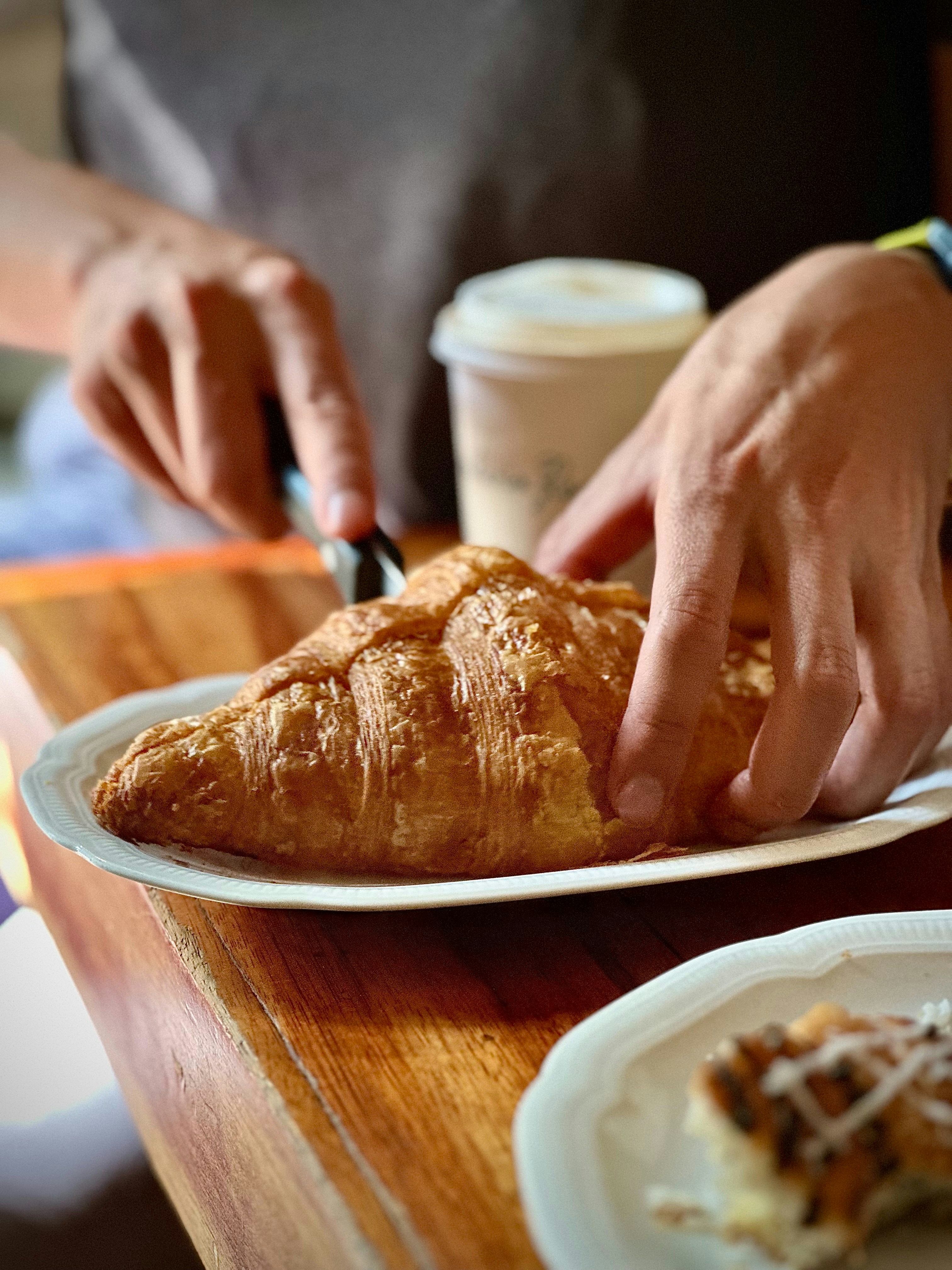 Someone is slicing a croissant for breakfast.